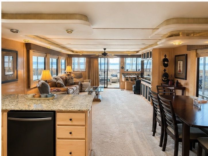 Interior of a luxurious houseboat cabin with living room, kitchen, and dining area.