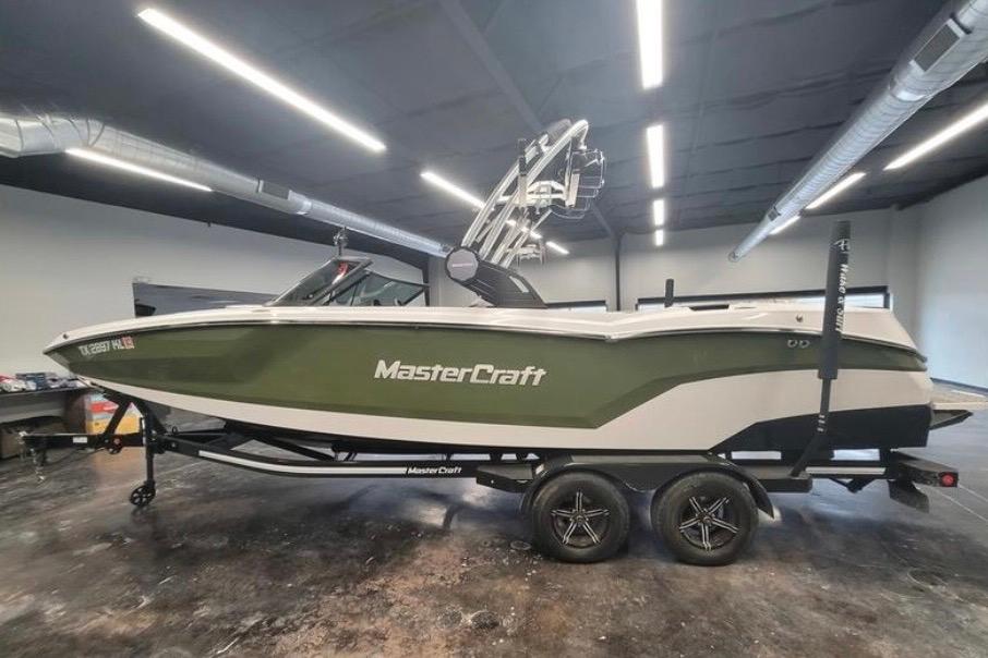 2022 MasterCraft NXT24 boat in showroom, green and white design, on trailer.