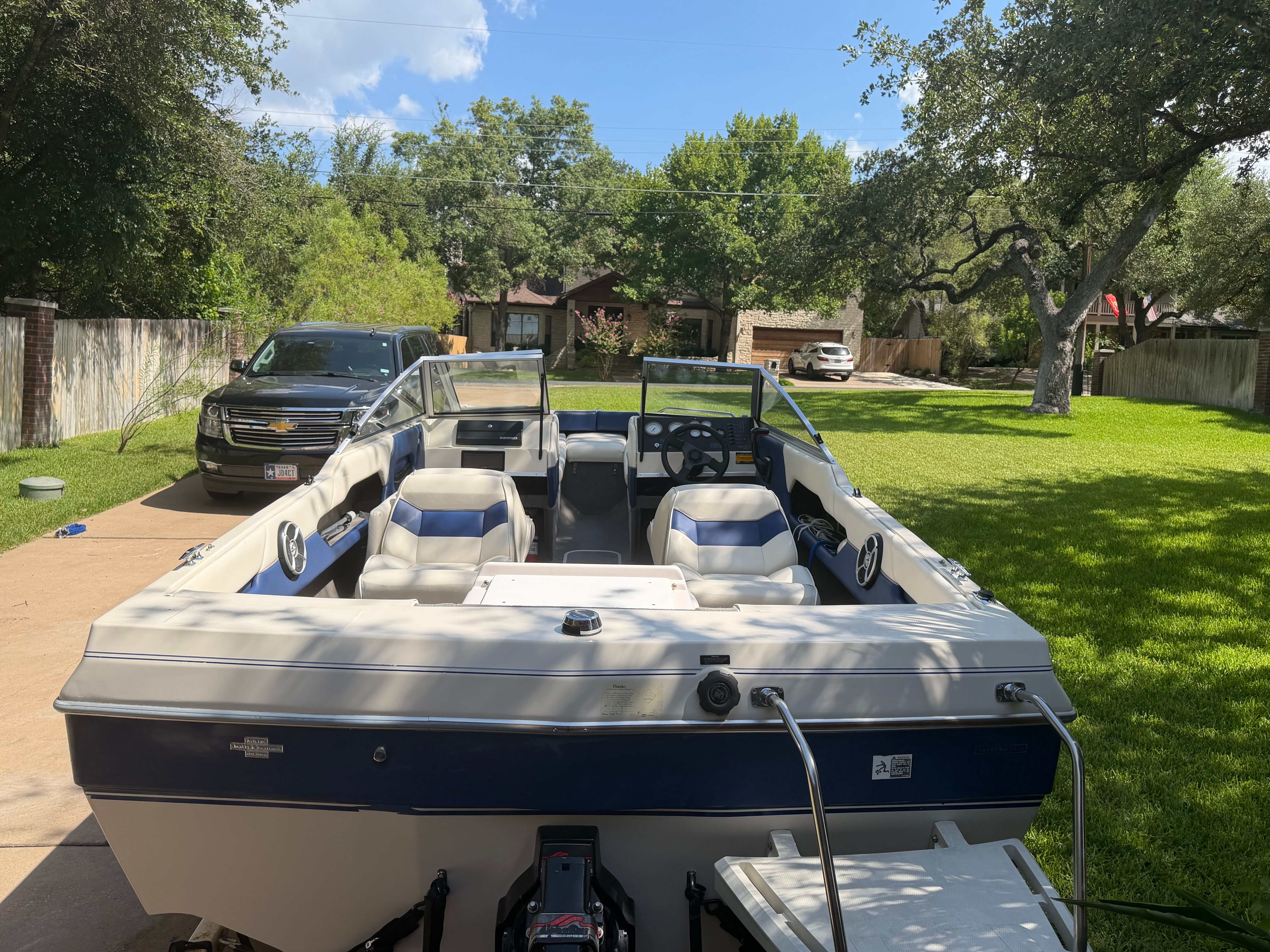 A 1994 Bayliner CAPRI on a driveway. It's an open motorboat with blue and white seating.