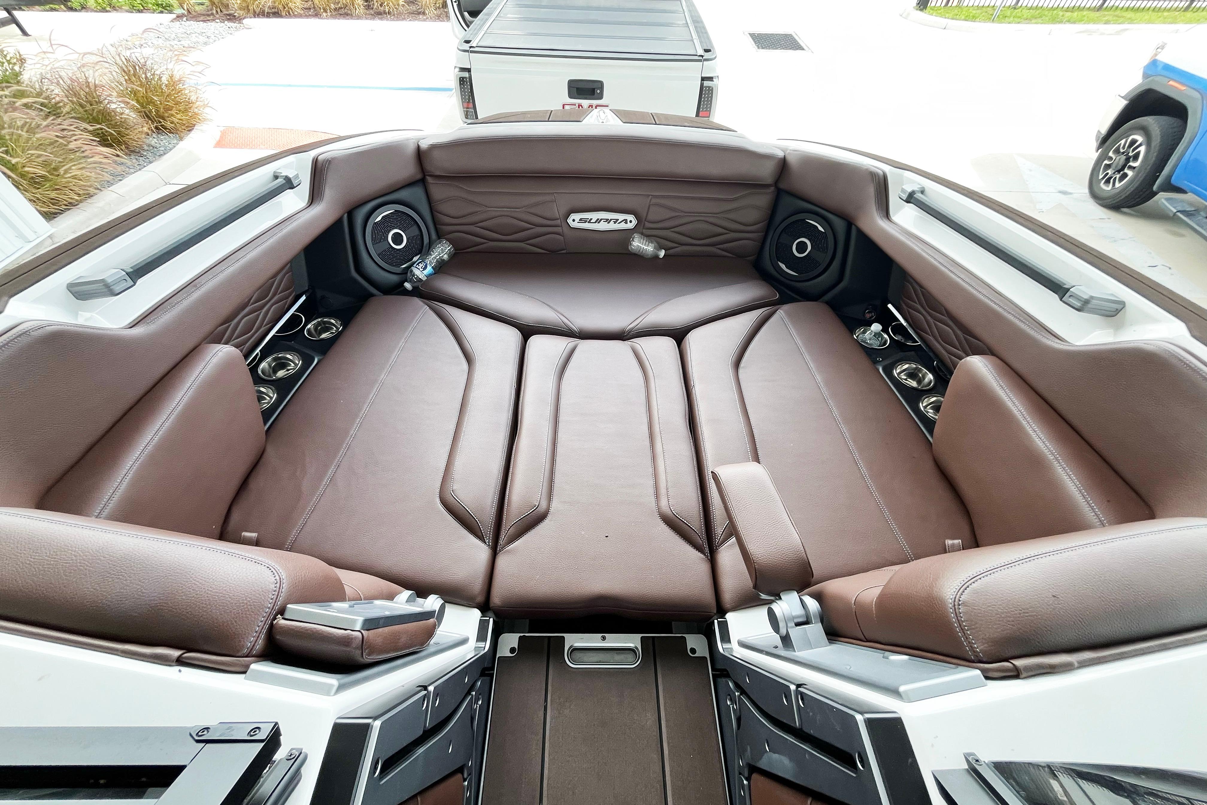 2025 Supra SA450 boat interior with brown leather seating and built-in speakers.