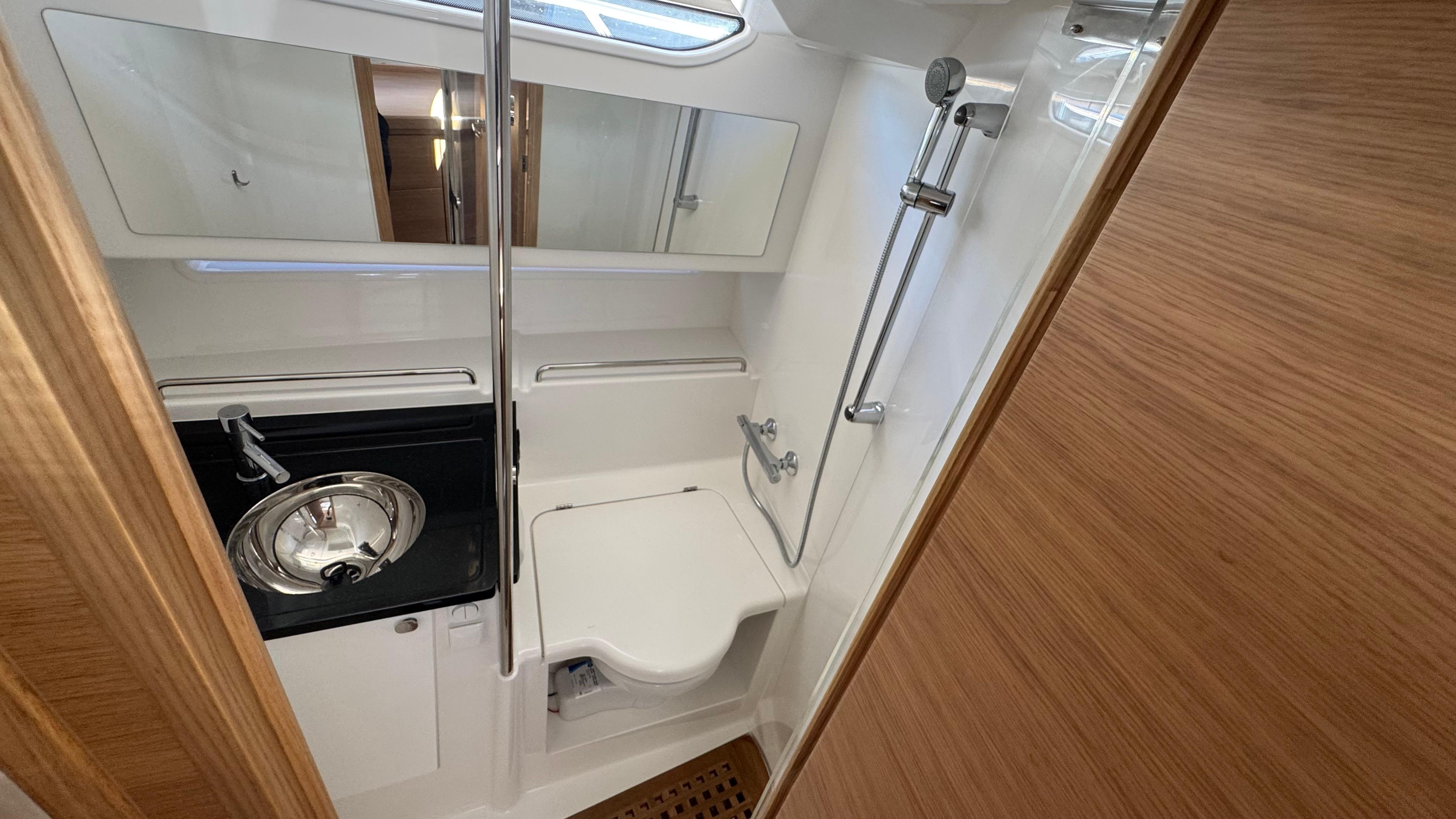2024 Nimbus W11 boat bathroom with sink, toilet, and shower in compact, modern design.