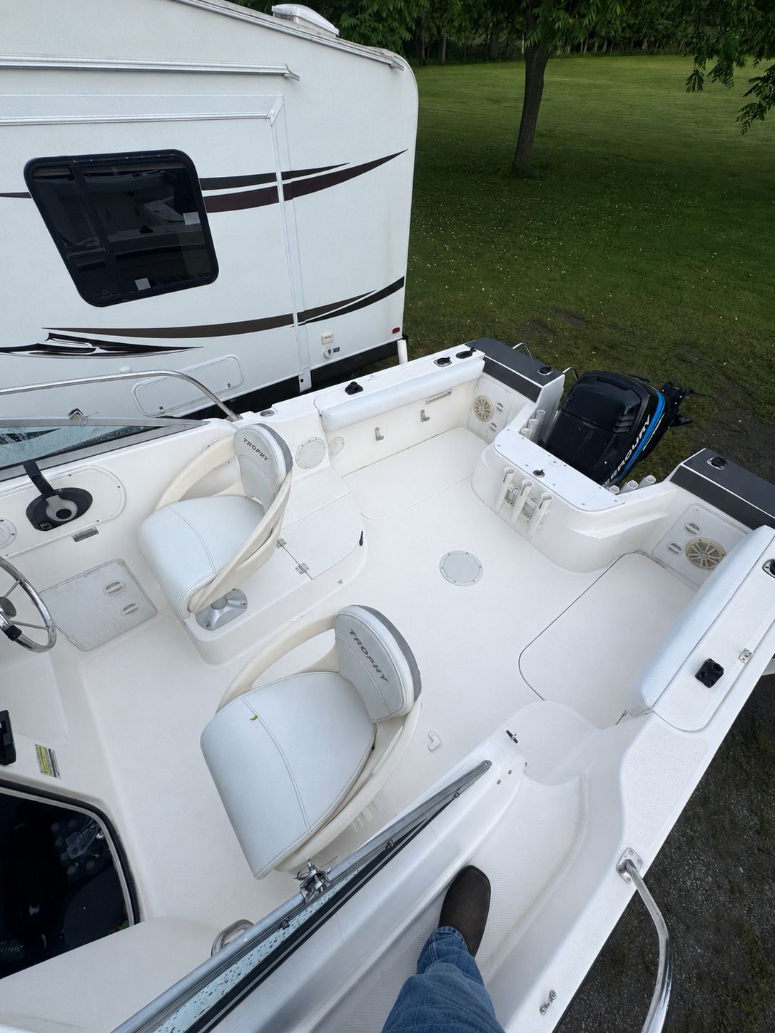 2005 Bayliner Trophy boat beside RV on grass.