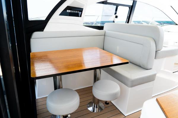 Interior of 2022 Bavaria SR41 yacht with wooden table and white seating.