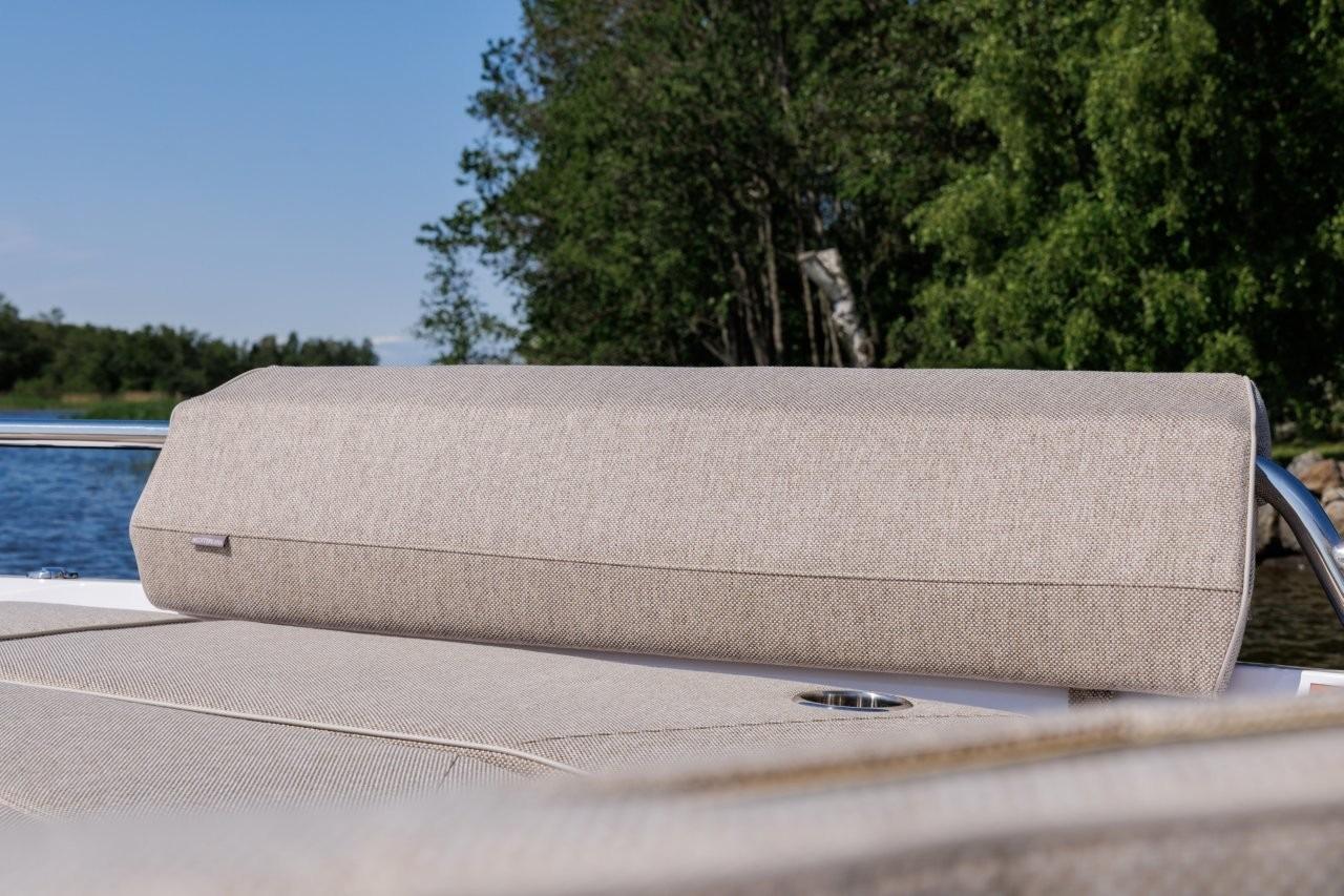 2026 Axopar 29XC Aft Sofa, beige upholstery, scenic lake view, lush greenery.