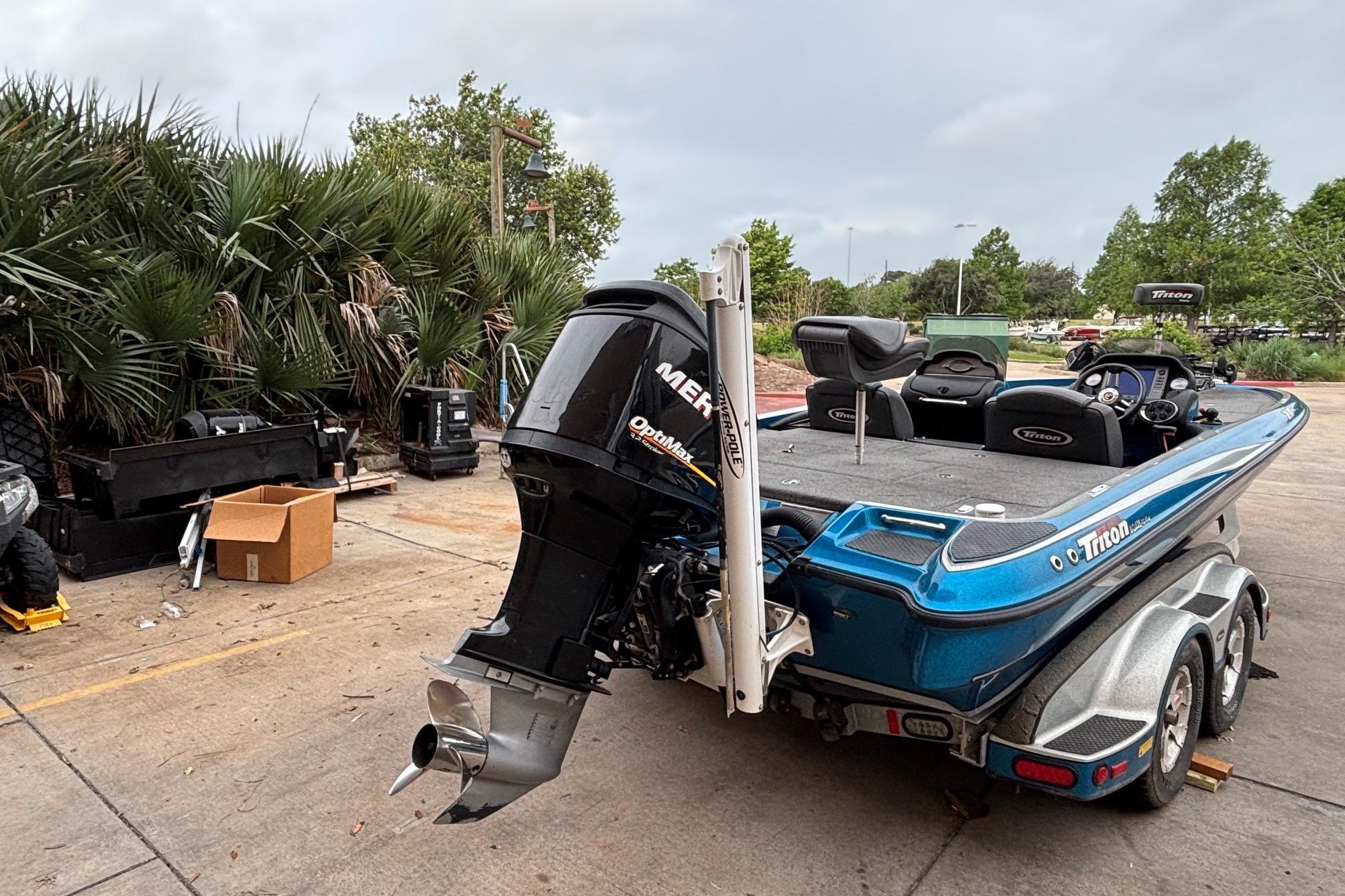 2009 Triton 22 TrX boat with Mercury outboard motor, parked outdoors near palm trees.