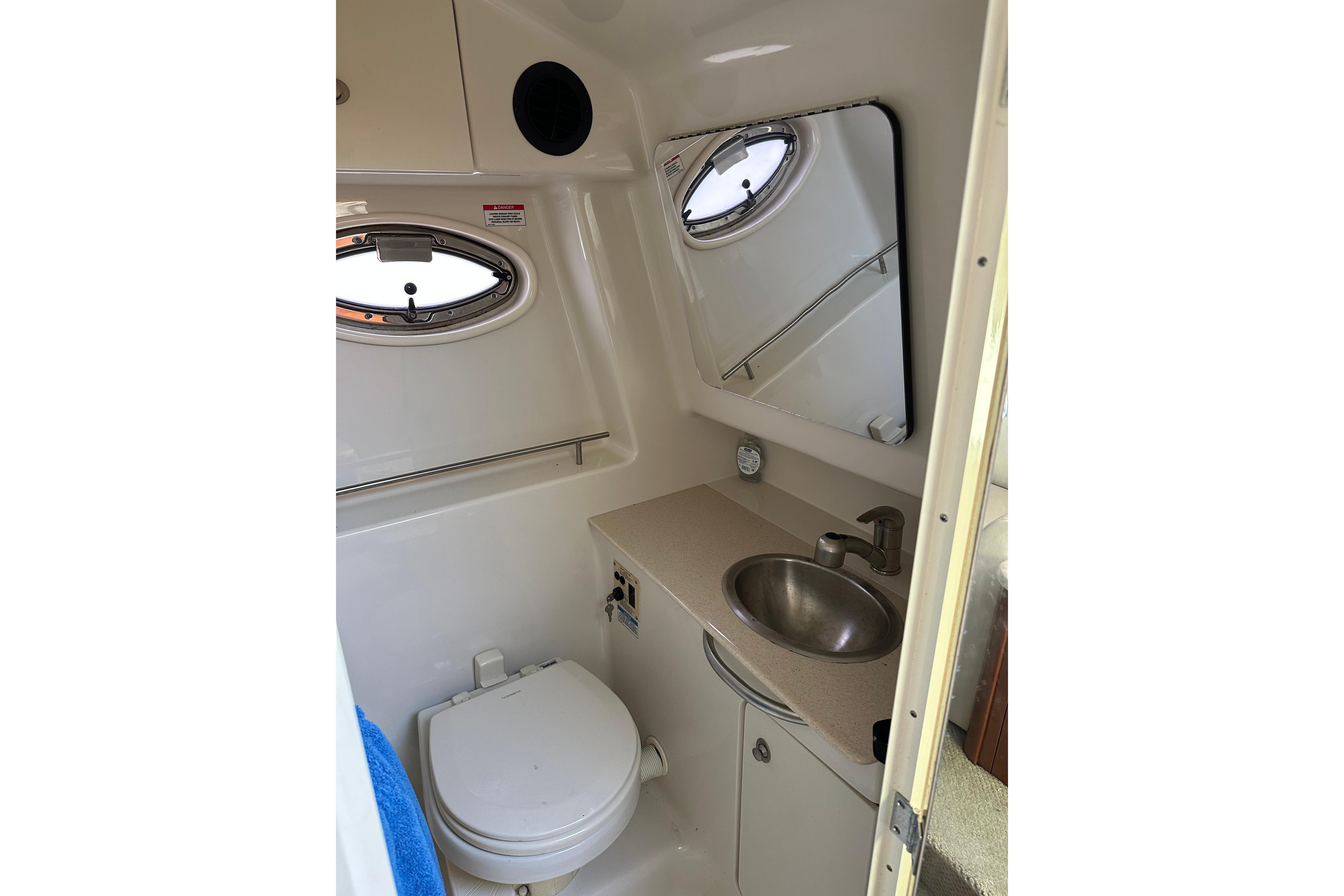 Compact bathroom in 2008 Sea Ray 290 Sundancer boat with sink, toilet, and mirror.