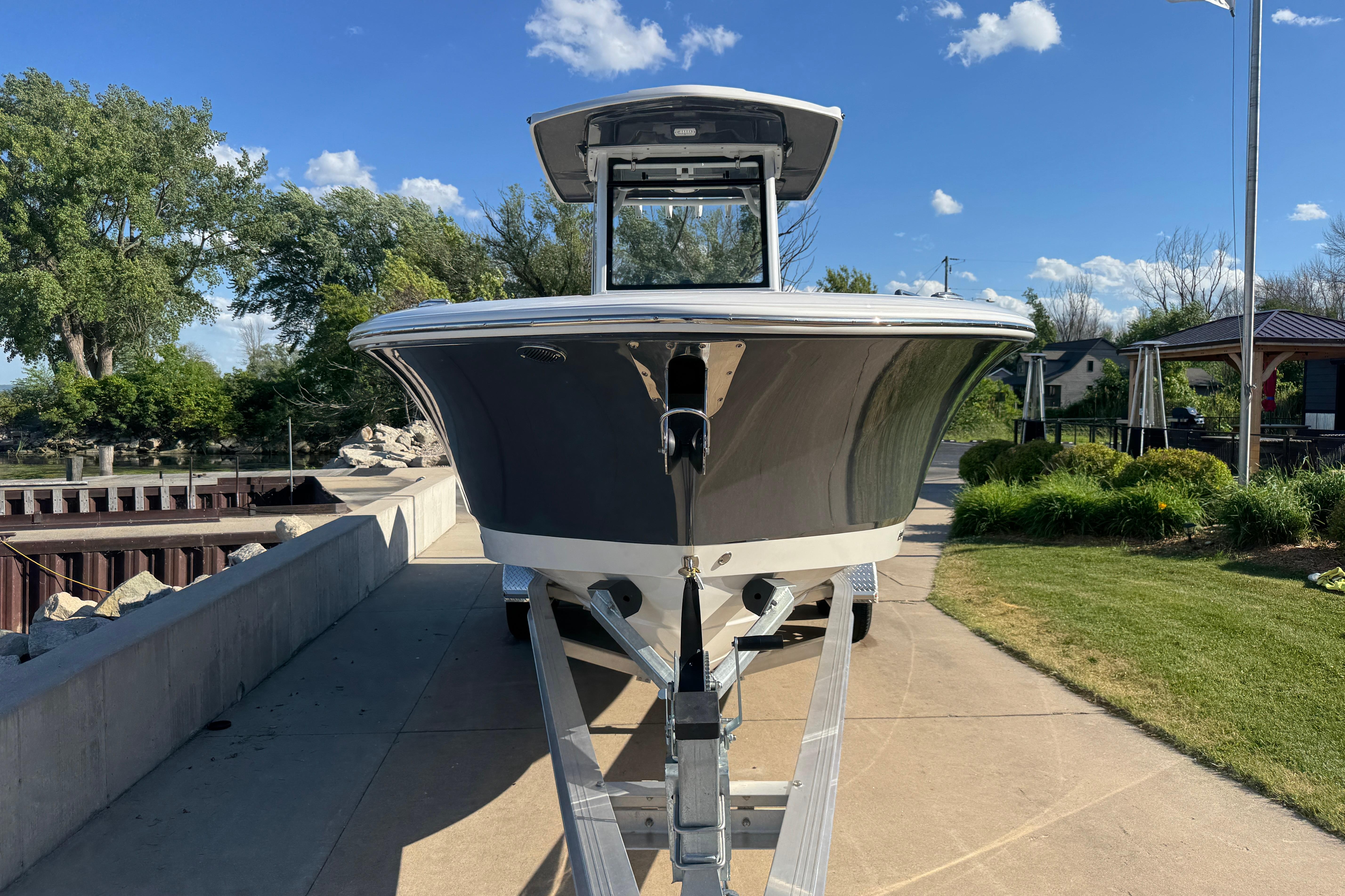 2026 Robalo R250 Center Console boat on trailer, parked outdoors under blue sky.