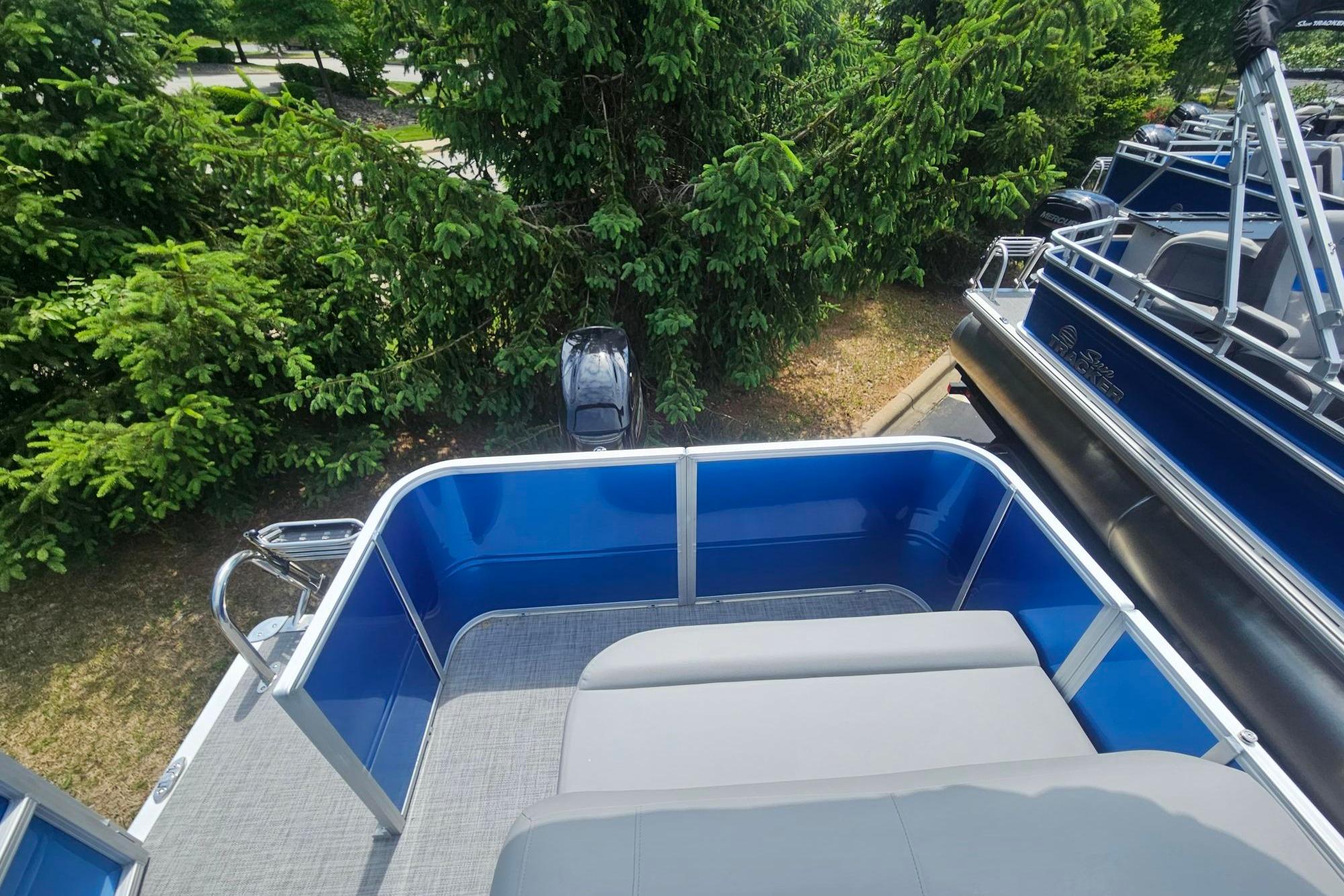2026 Sun Tracker Party Barge 18 DLX pontoon boat with blue exterior and seating area.