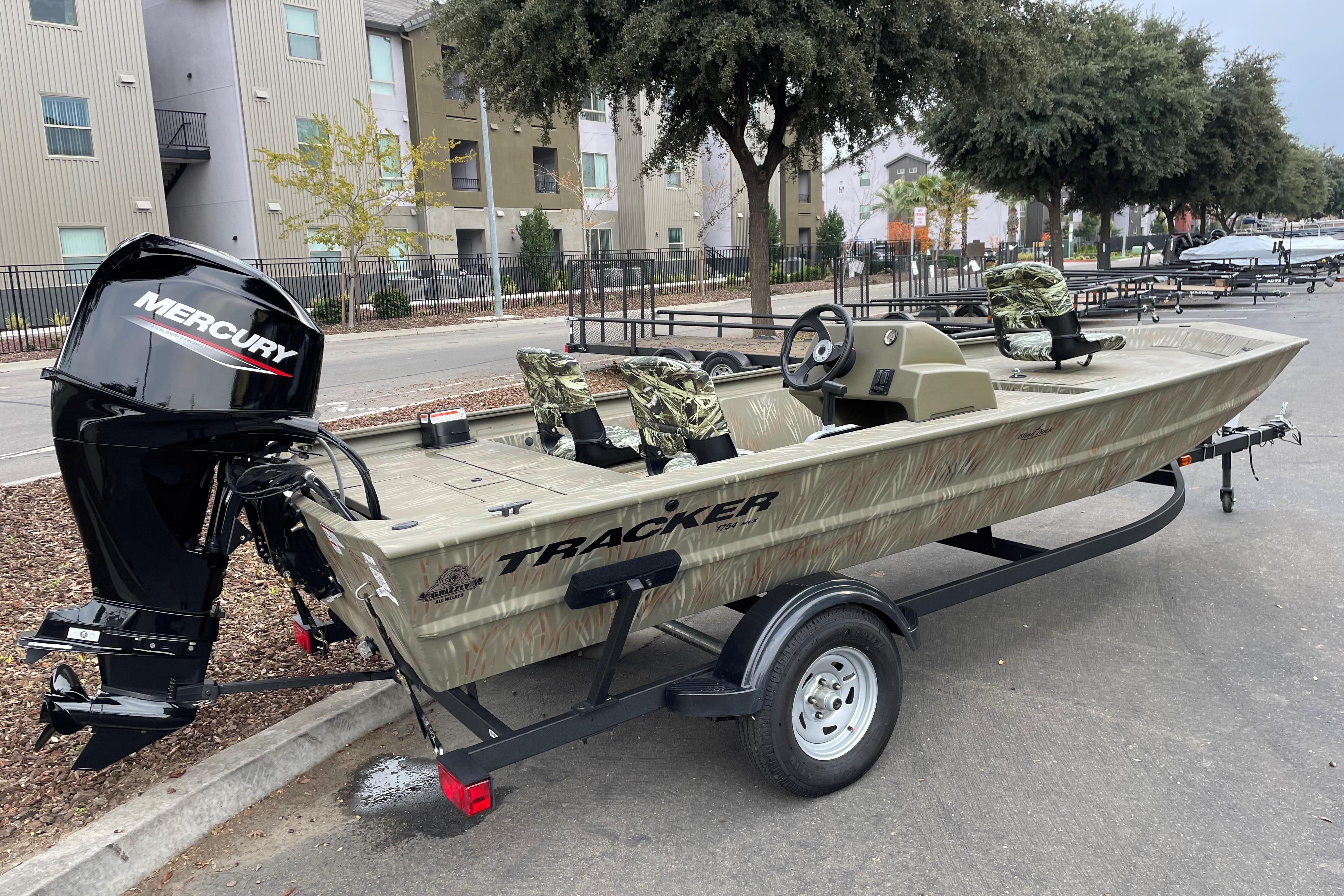 2025 Tracker Grizzly 1754 SC boat with Mercury engine on trailer, parked outdoors.