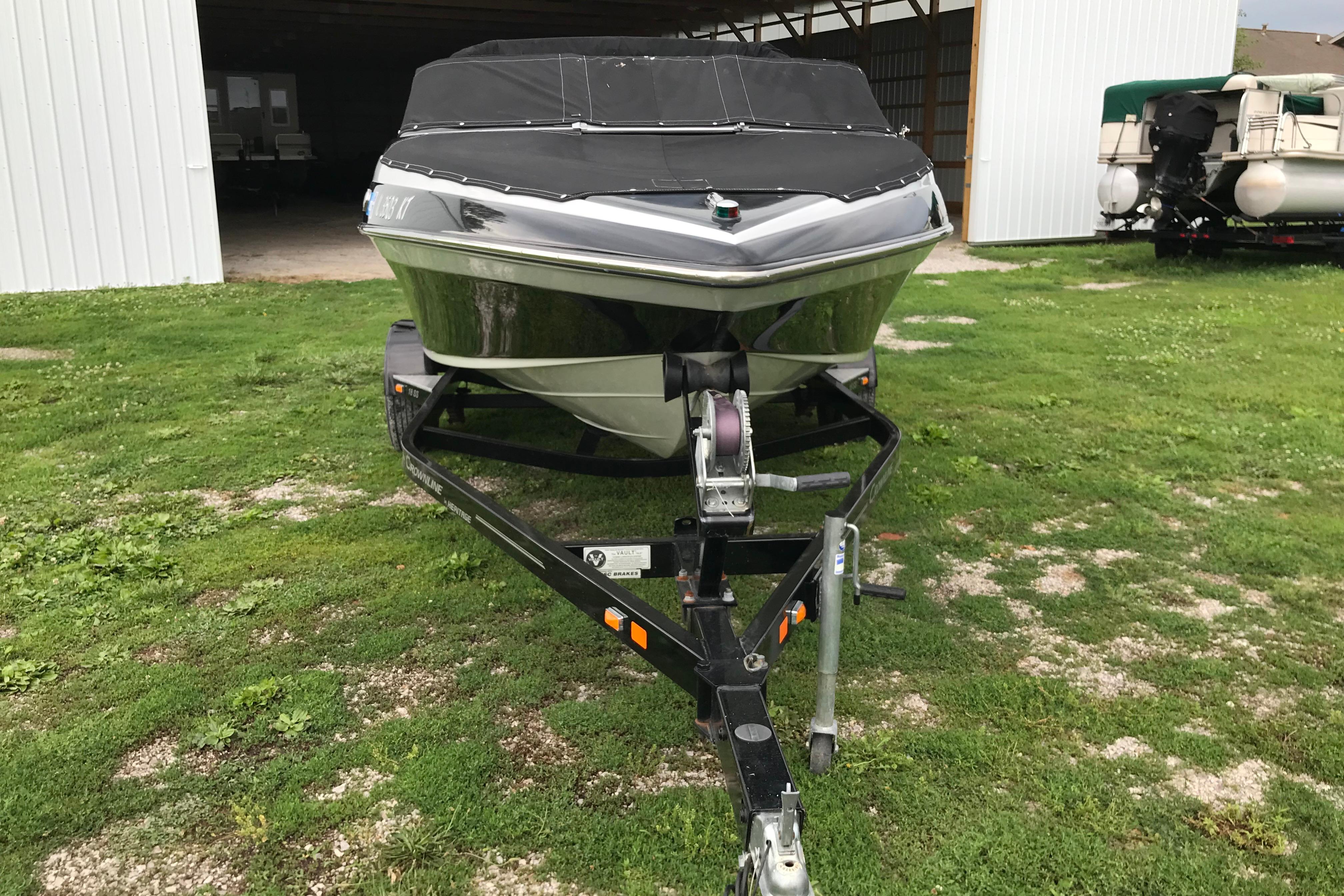 2015 Crownline 18 SS boat on trailer, parked on grassy area near a building.