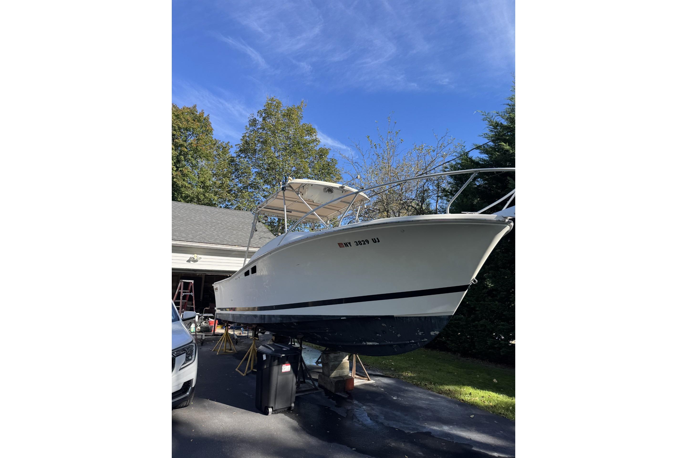 1993 Luhr's Tournament boat on trailer, parked in driveway under clear blue sky.