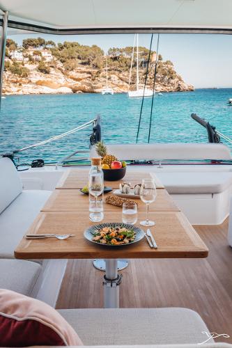 Luxurious Nautitech 44 Open yacht interior with dining setup, overlooking serene turquoise waters, 2025 model.