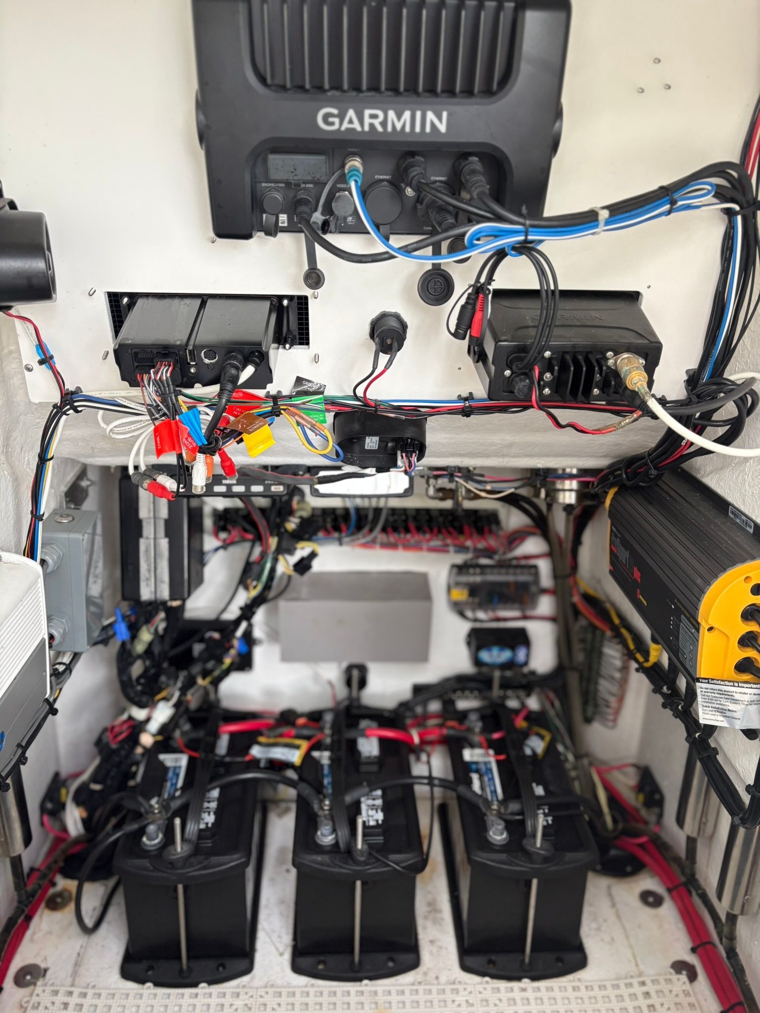 Electronics and batteries in a boat with Garmin device and wiring.