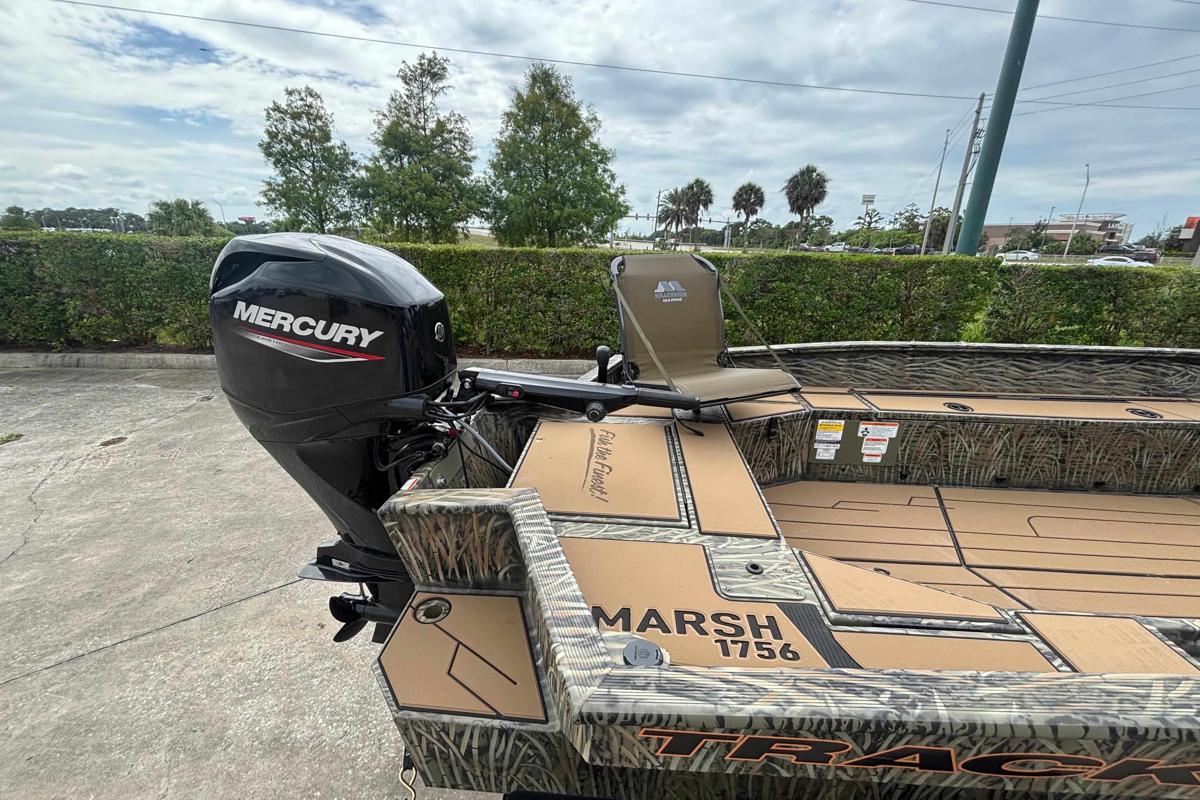 2026 Tracker Grizzly 1756 T Marsh boat with Mercury outboard motor in a parking lot.