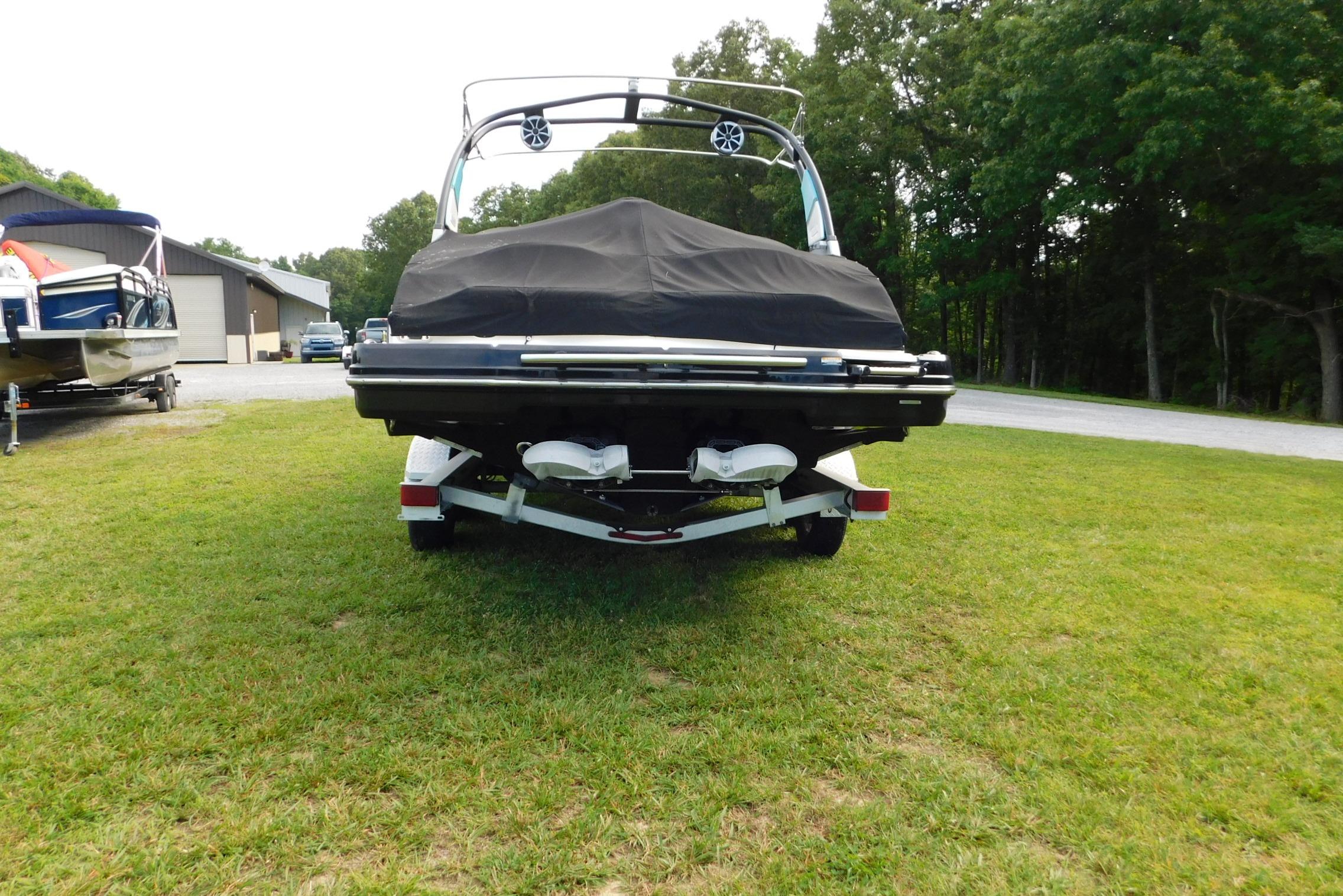 2016 CHAPPARRAL 243 boat with cover, parked on grass near trees and buildings.