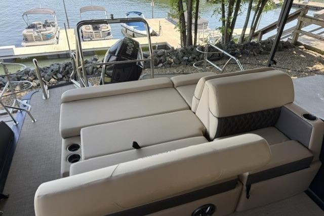 2025 Harris Sunliner 230 boat with beige seating, docked by a serene lakeside.