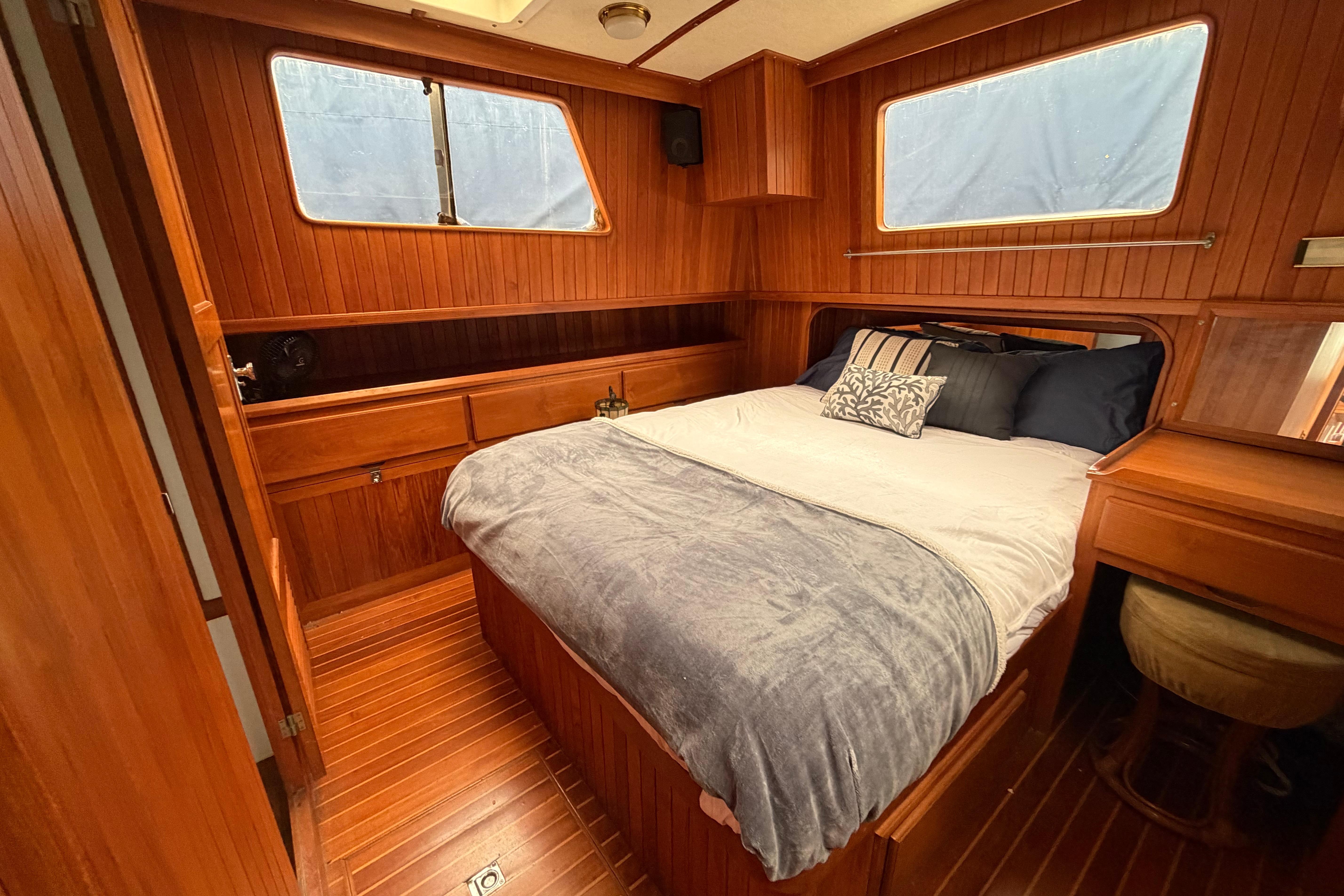 Cozy wooden cabin interior of 1988 Monk 36 boat with bed and desk.