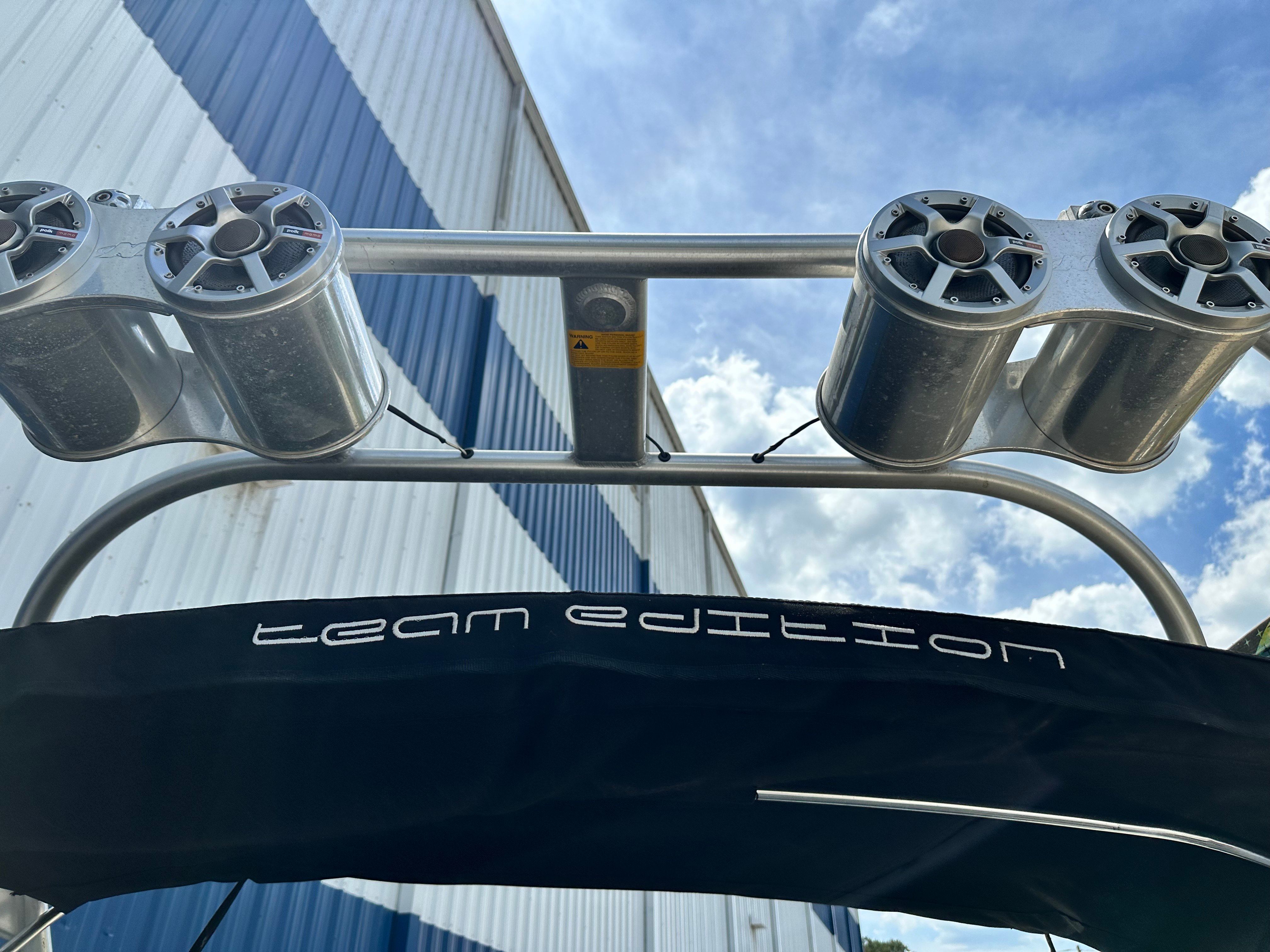 Close-up of a boat tower with speakers and a black canopy, against a building.