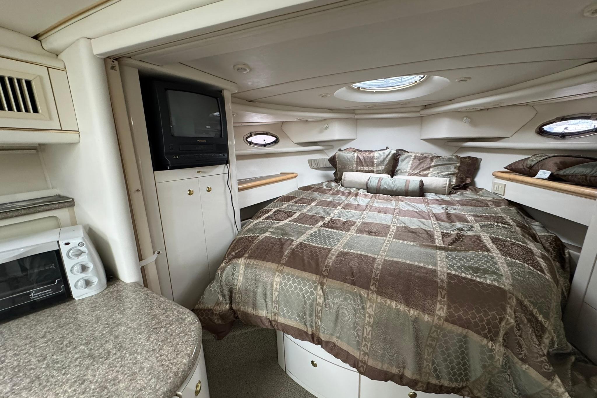 1998 Maxum 3700 SCR cabin interior with bed, TV, and microwave.
