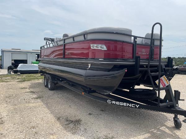 2023 Regency 250DL3 pontoon boat on trailer, red and black design, parked outdoors.