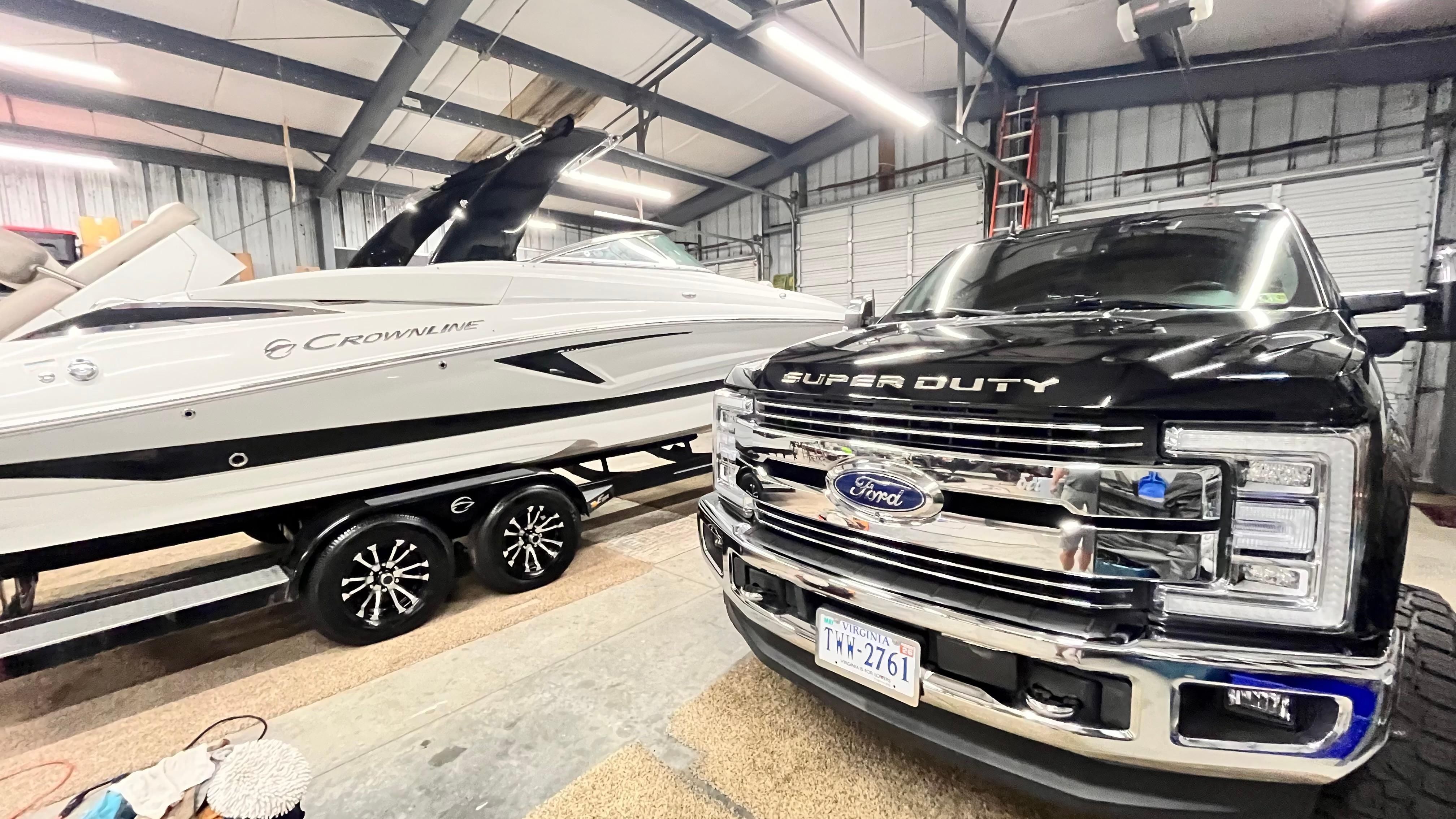 A 2019 Crownline E 285 boat is in a warehouse next to a Ford Super Duty truck.