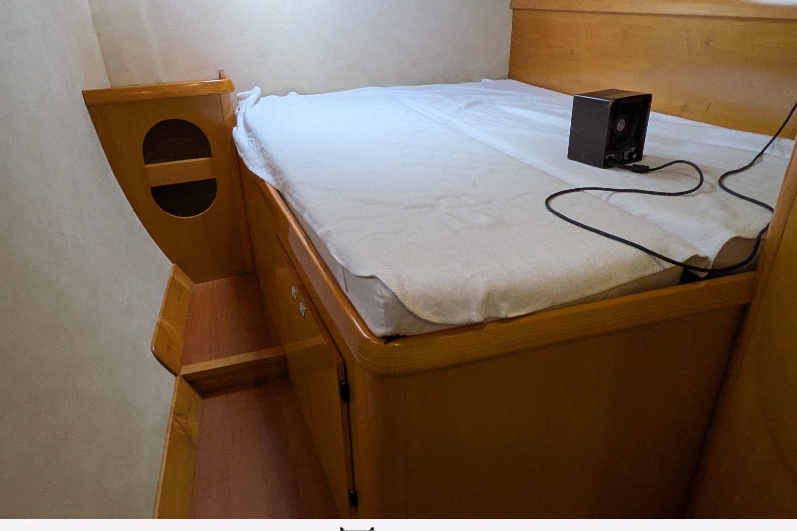 Cozy cabin interior of 2006 Fountaine Pajot Belize 43 catamaran with wooden bed and speaker.