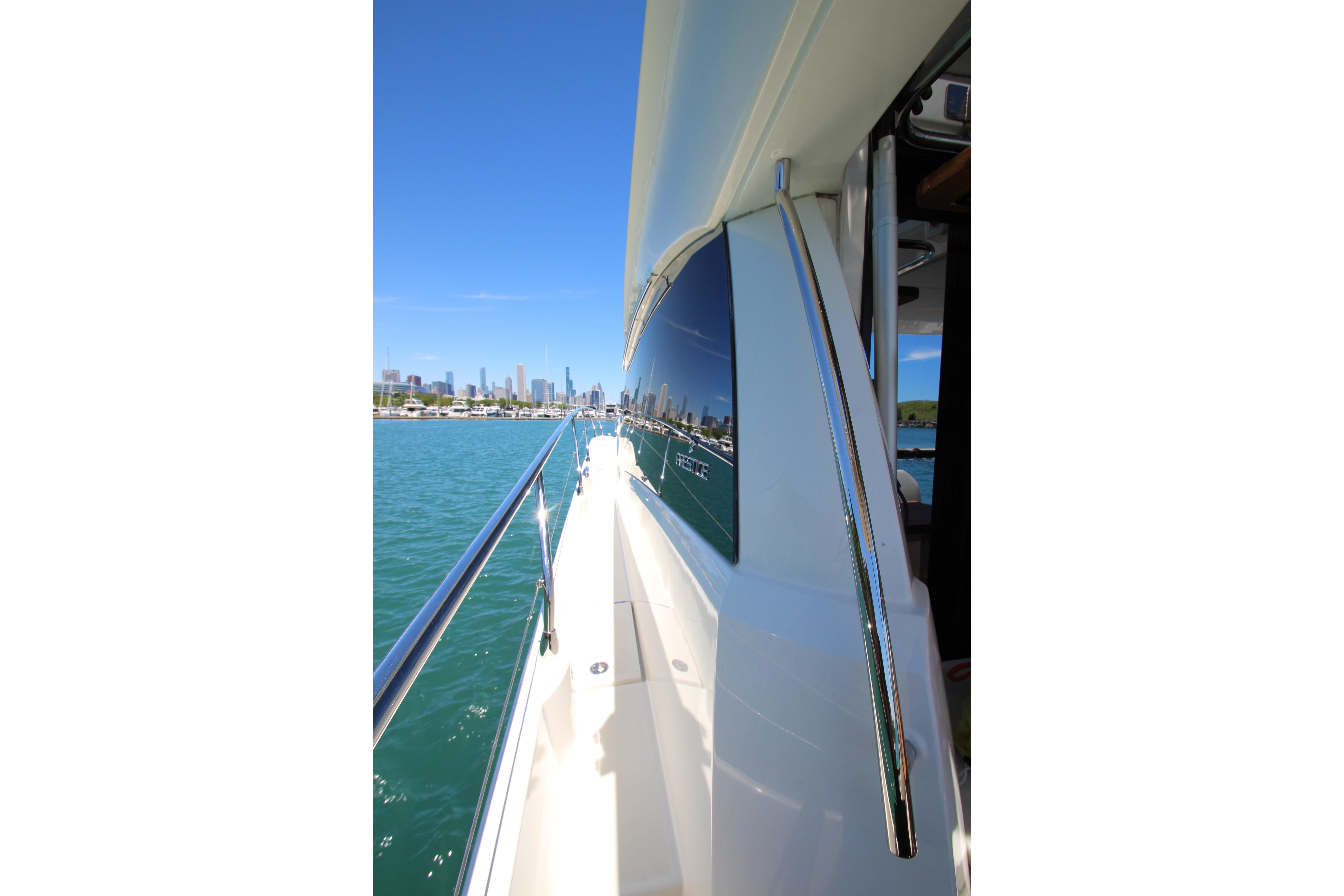 Side view of 2022 Prestige 520 yacht cruising near city skyline.