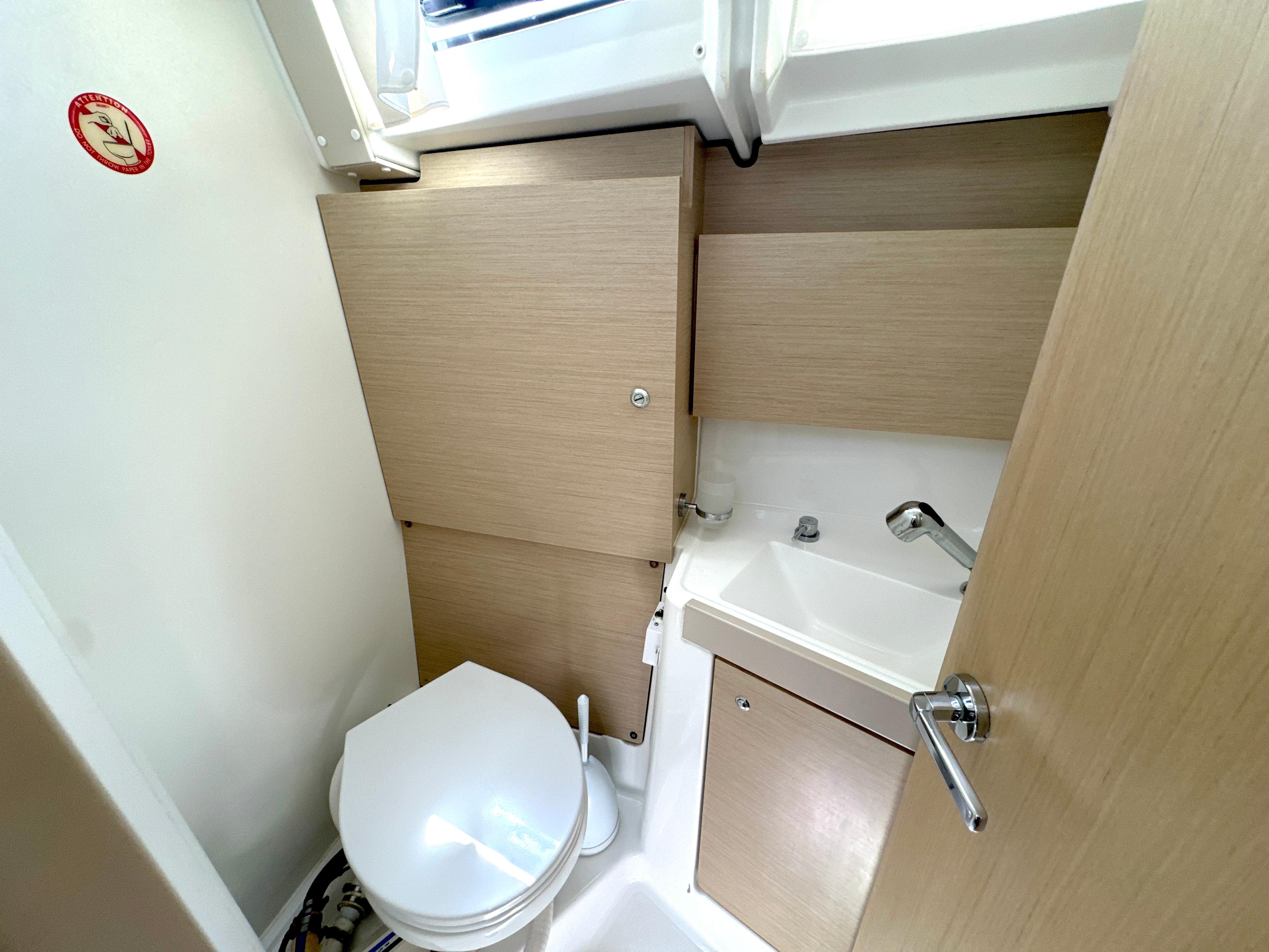 Bathroom interior of 2021 Beneteau Oceanis 38.1 yacht, featuring toilet and sink.