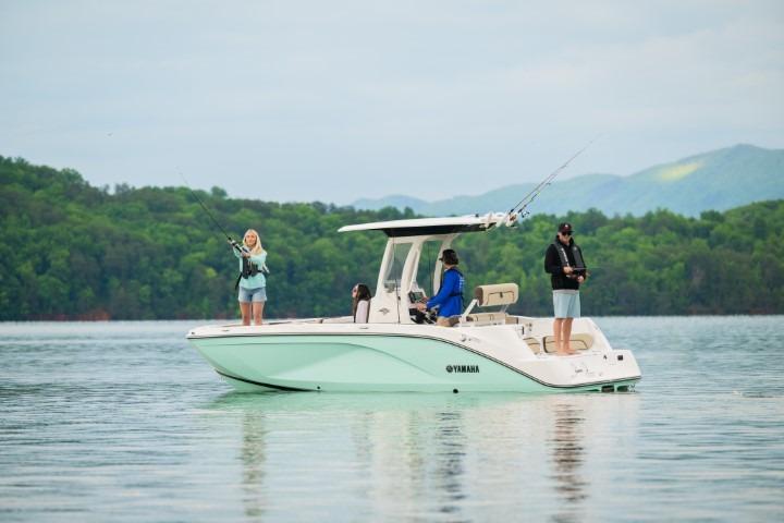 2026 Yamaha Boats 222 FSH Sport E on a serene lake with people fishing.