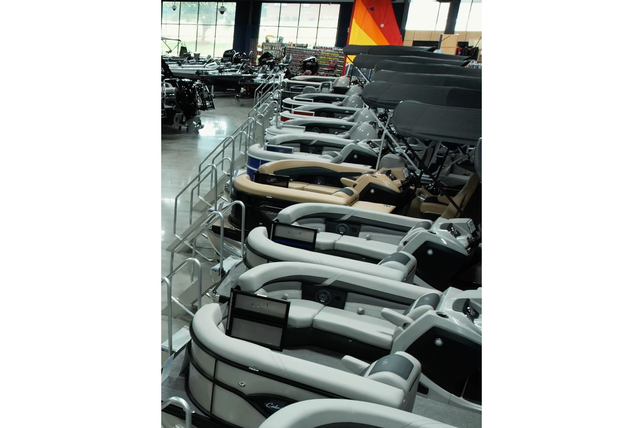 Showroom display of 2025 Barletta Lusso 23UC pontoon boats in various colors.