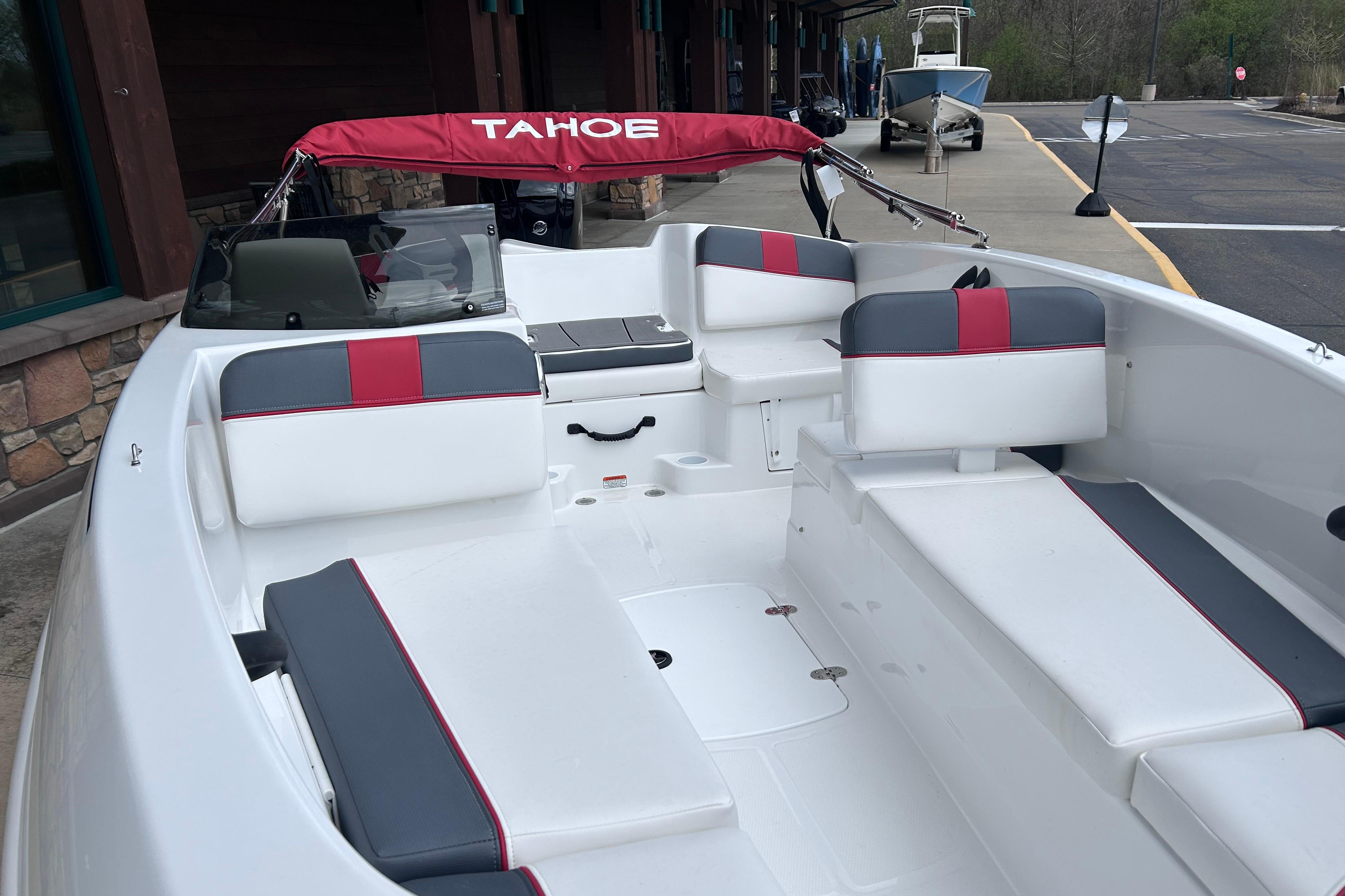 2026 Tahoe T16 boat interior with red and gray seating, docked near a building.