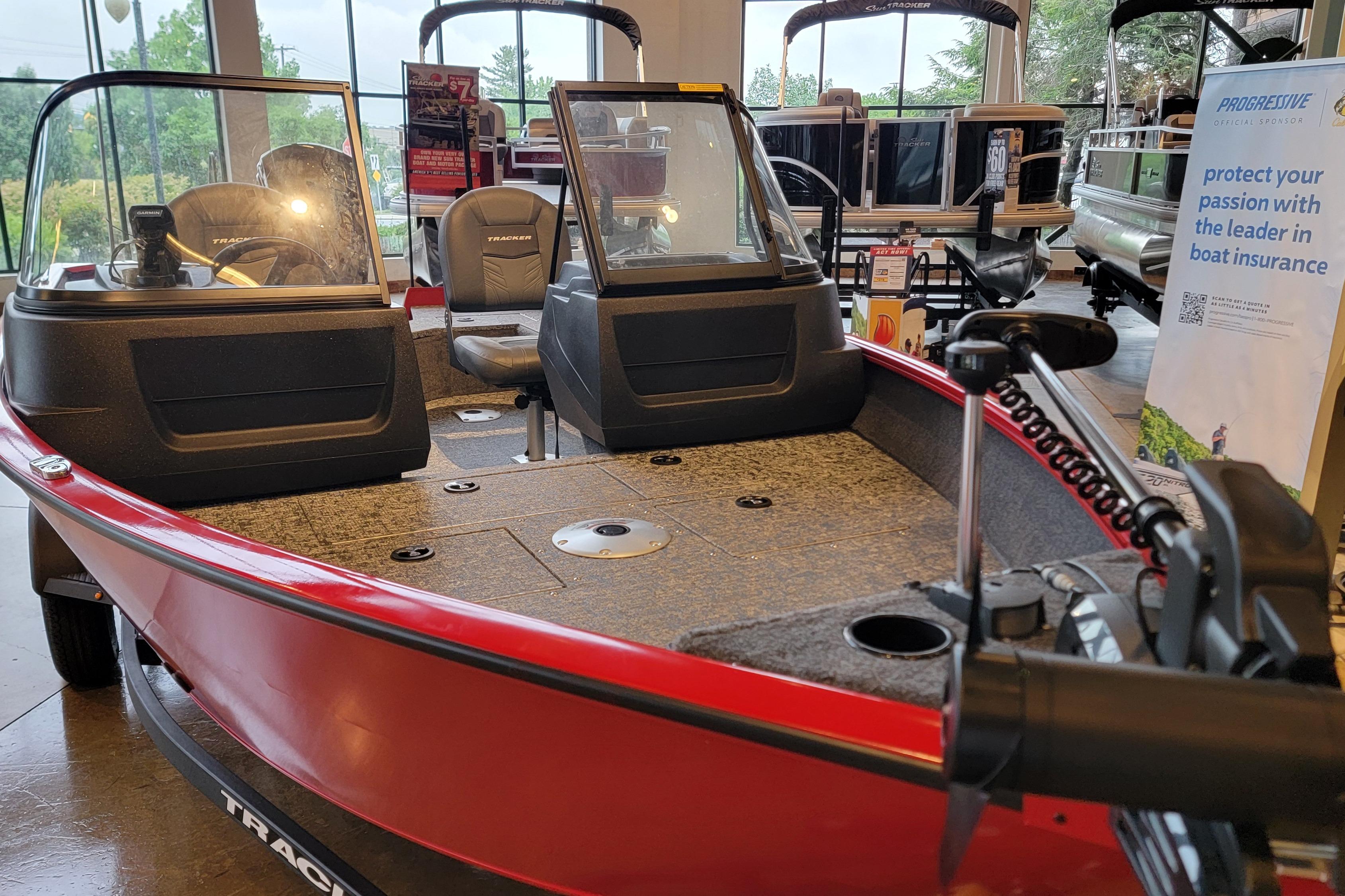 2026 Tracker Pro Guide V-16 WT boat displayed indoors, featuring red exterior and spacious interior.