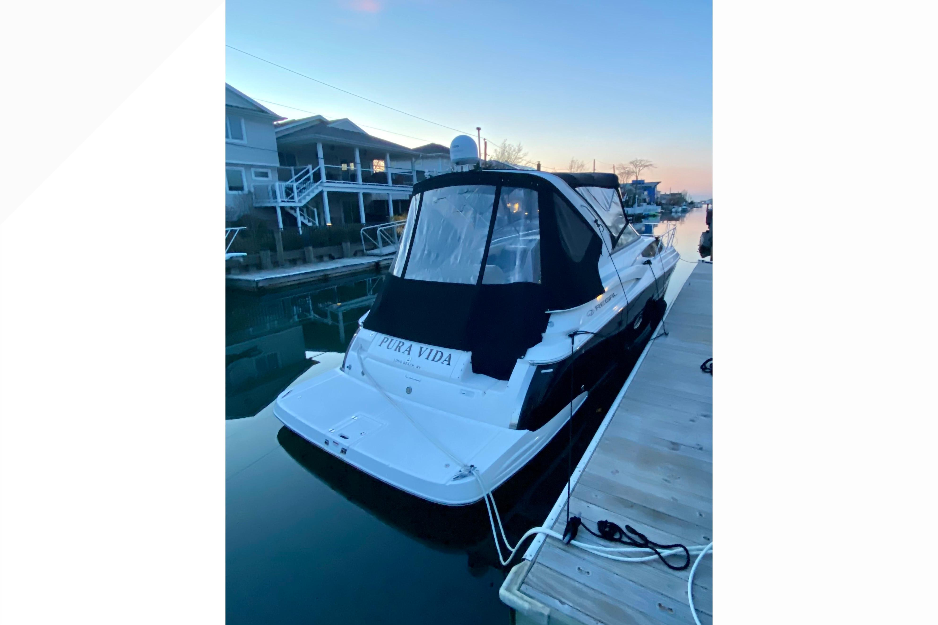 2012 Regal 35 Express Cruiser docked at sunset, featuring sleek design and covered cockpit.