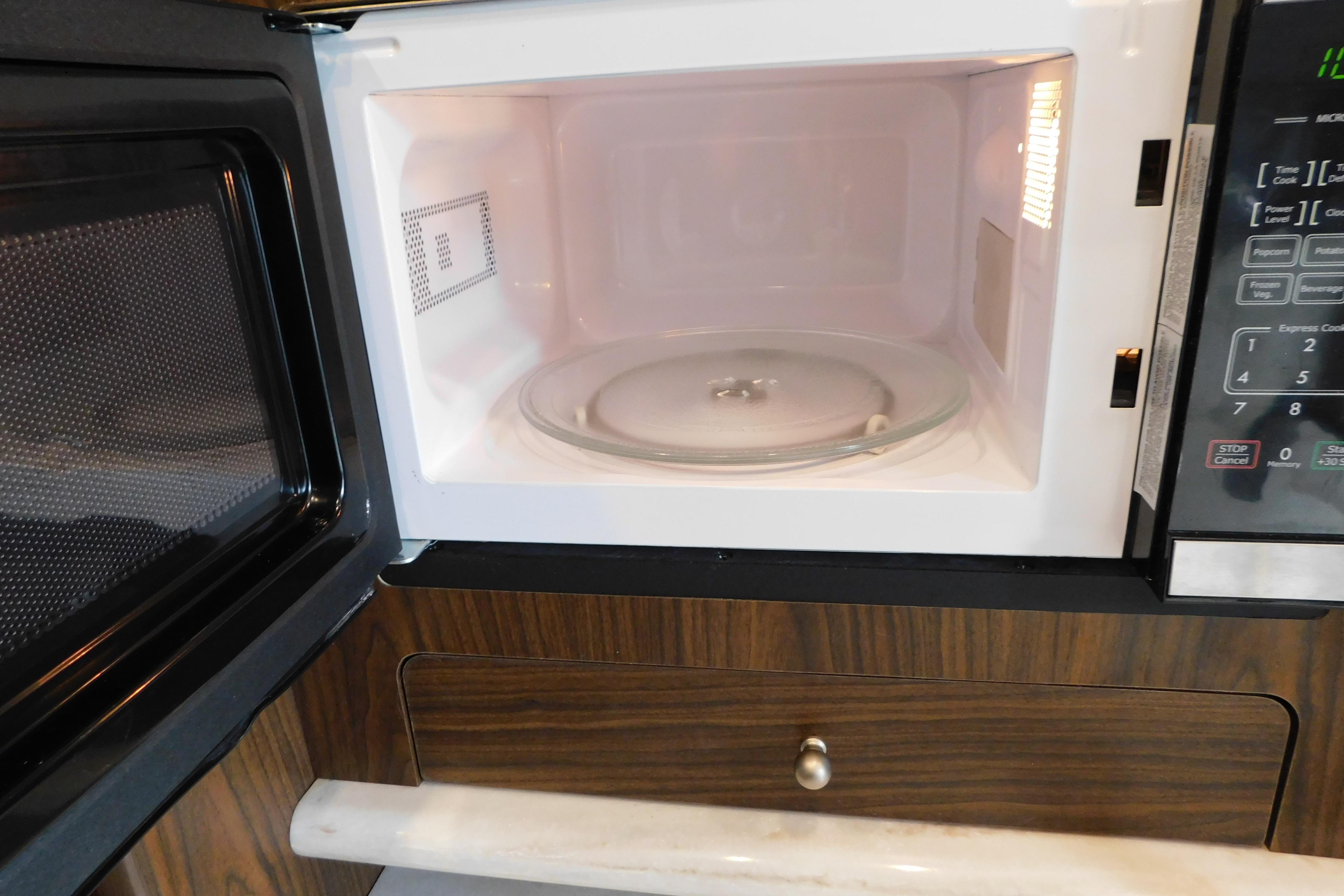 Open microwave oven inside a 2017 Rinker EX 320 boat kitchen.