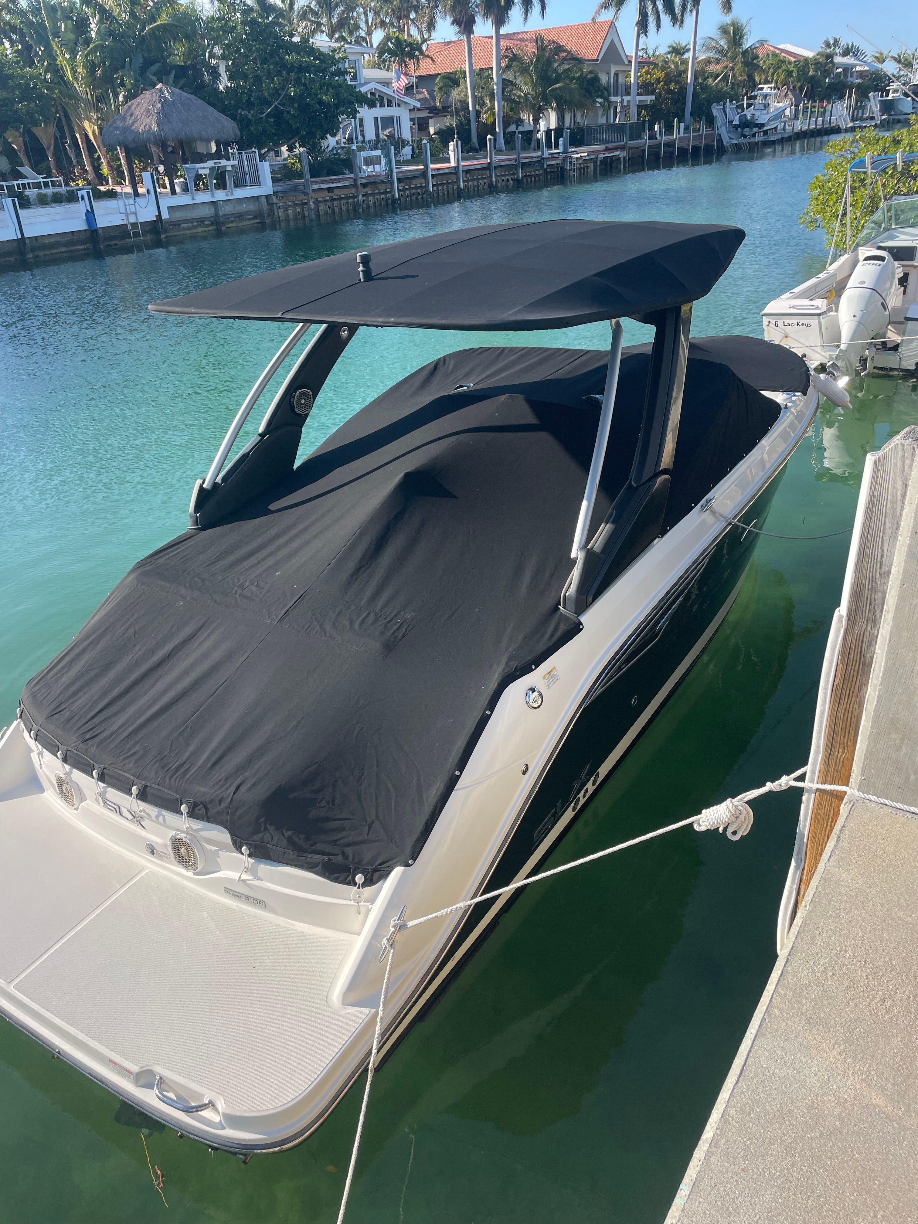 A Sea Ray SLX 250 boat docked at a pier in clear water.