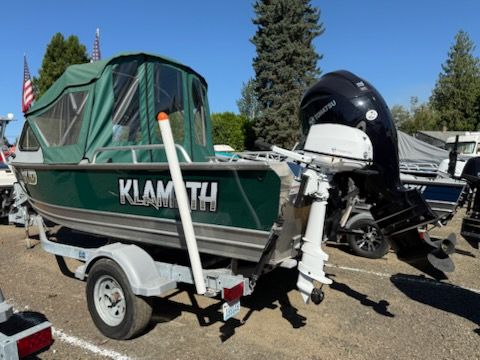 2019 Klamath 19 GTX boat with green canopy and outboard motor on trailer.