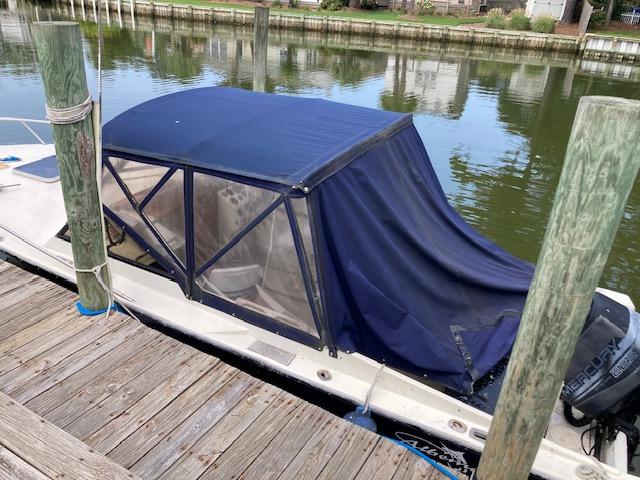 1982 Albemarle 24 boat with blue canopy docked by a wooden pier.