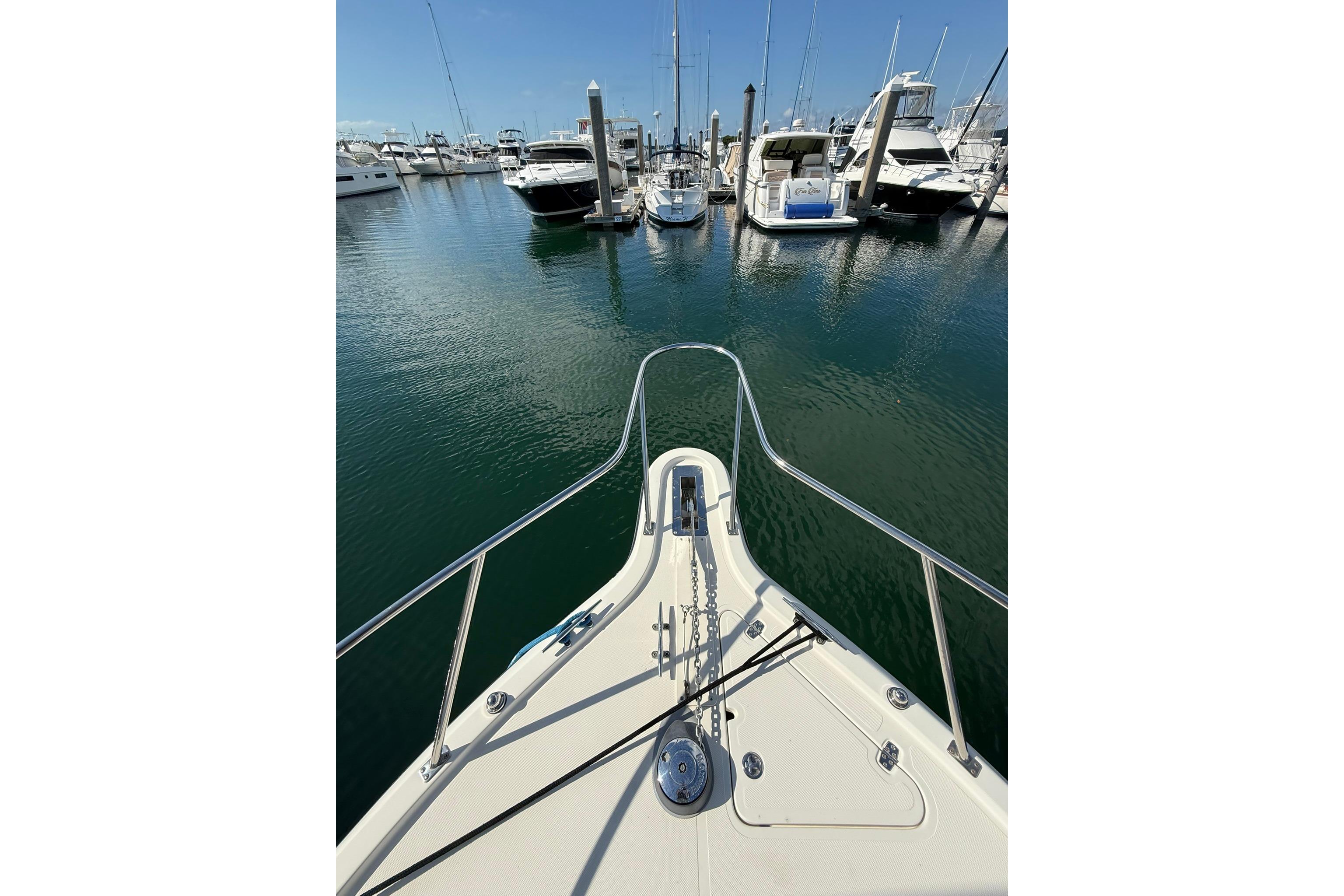 Bow view of 2004 Pursuit 3370 Offshore in a marina, surrounded by boats.