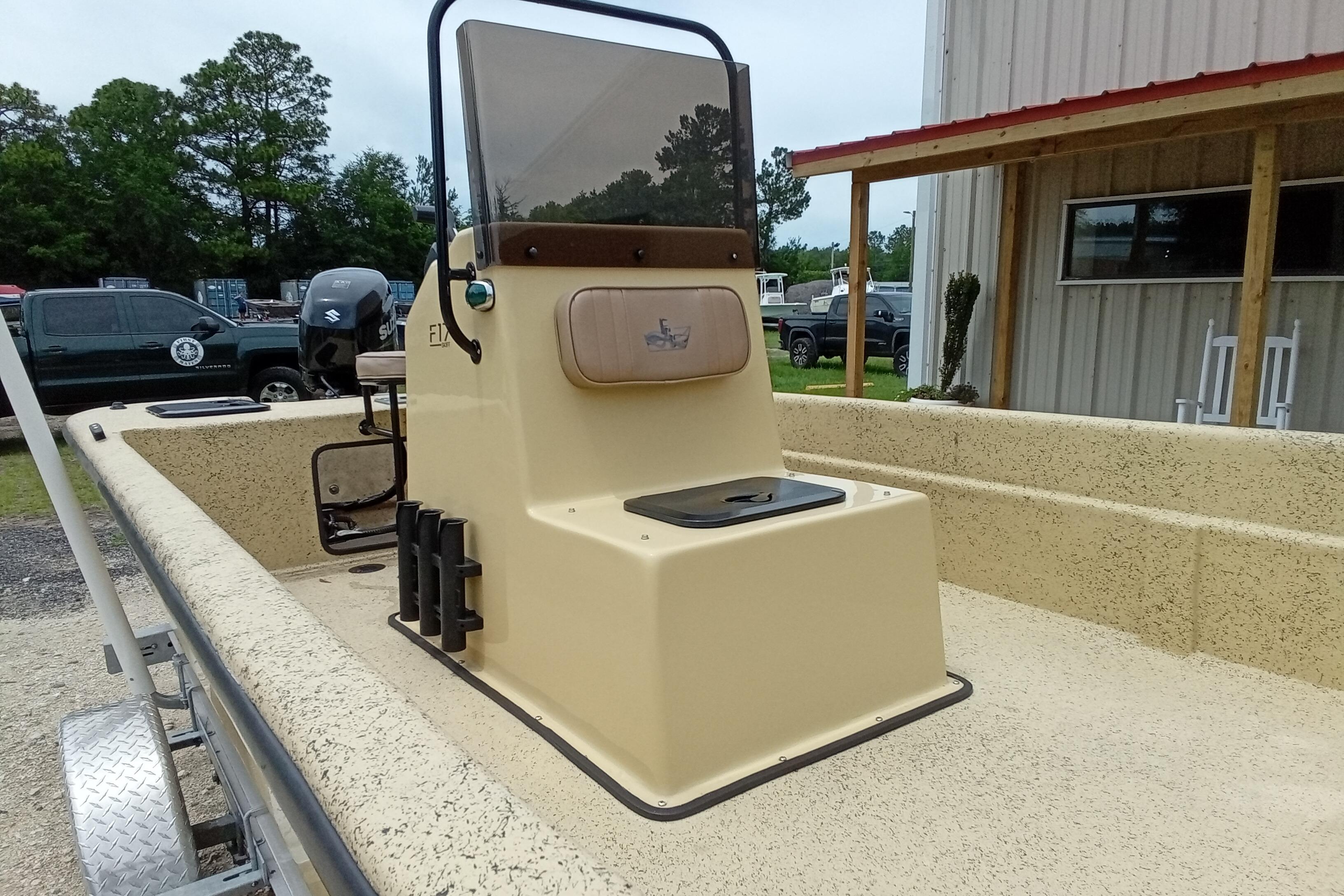 2025 Fibercraft F17 boat with beige interior, parked outdoors near a building.