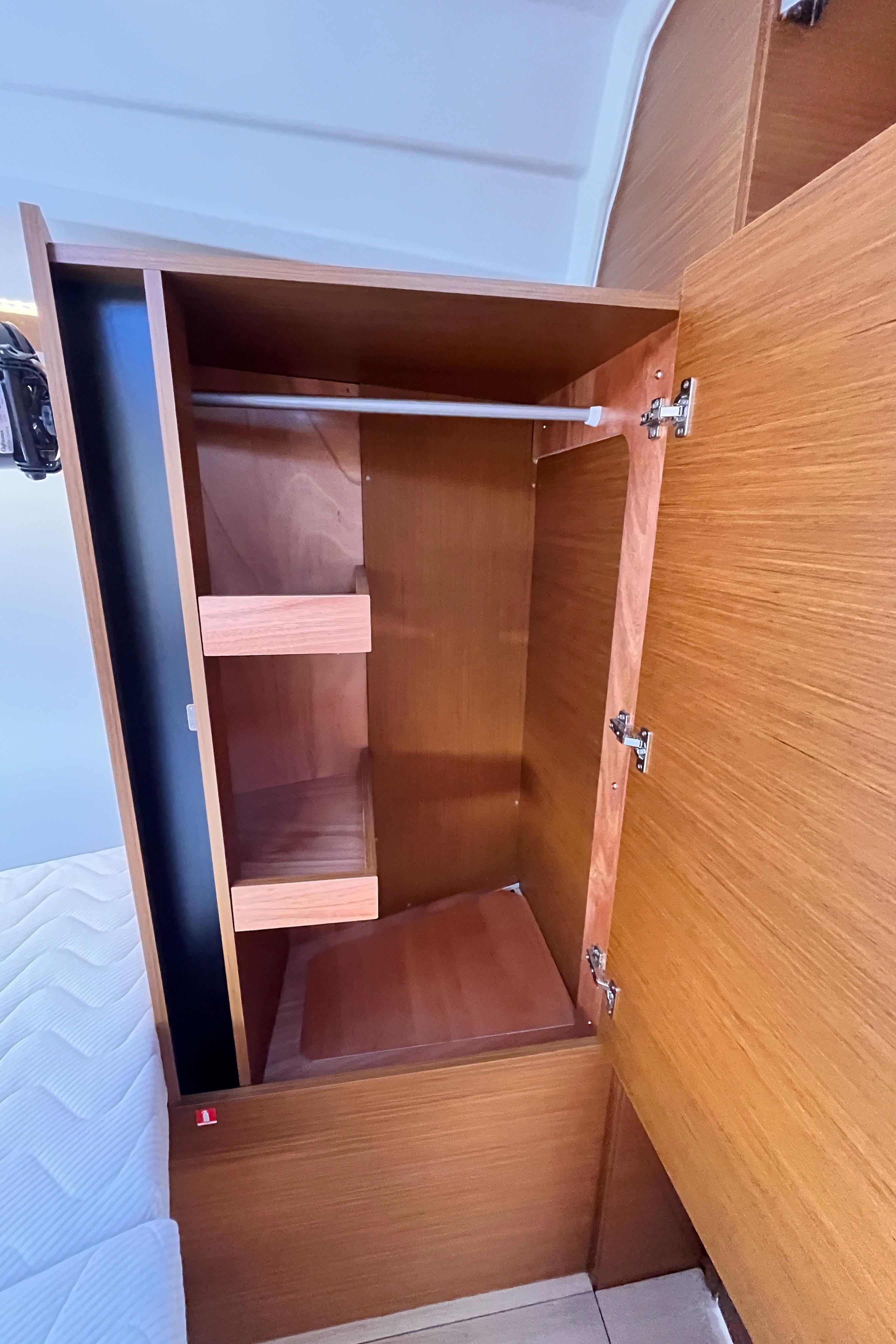 2024 Jeanneau 380 interior wooden cabinet with shelves and hanging rod.