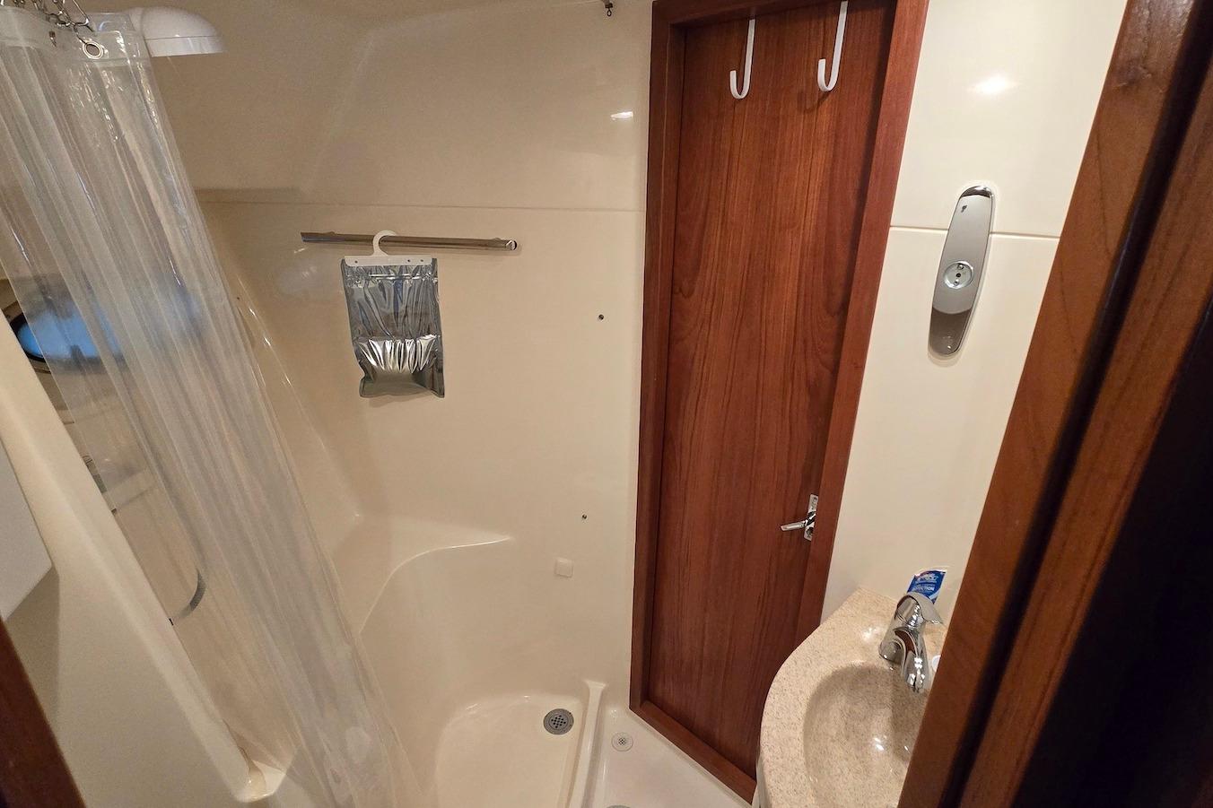 Bathroom interior of a 1996 Tiara Yachts 3700 Open, featuring a shower and wooden door.