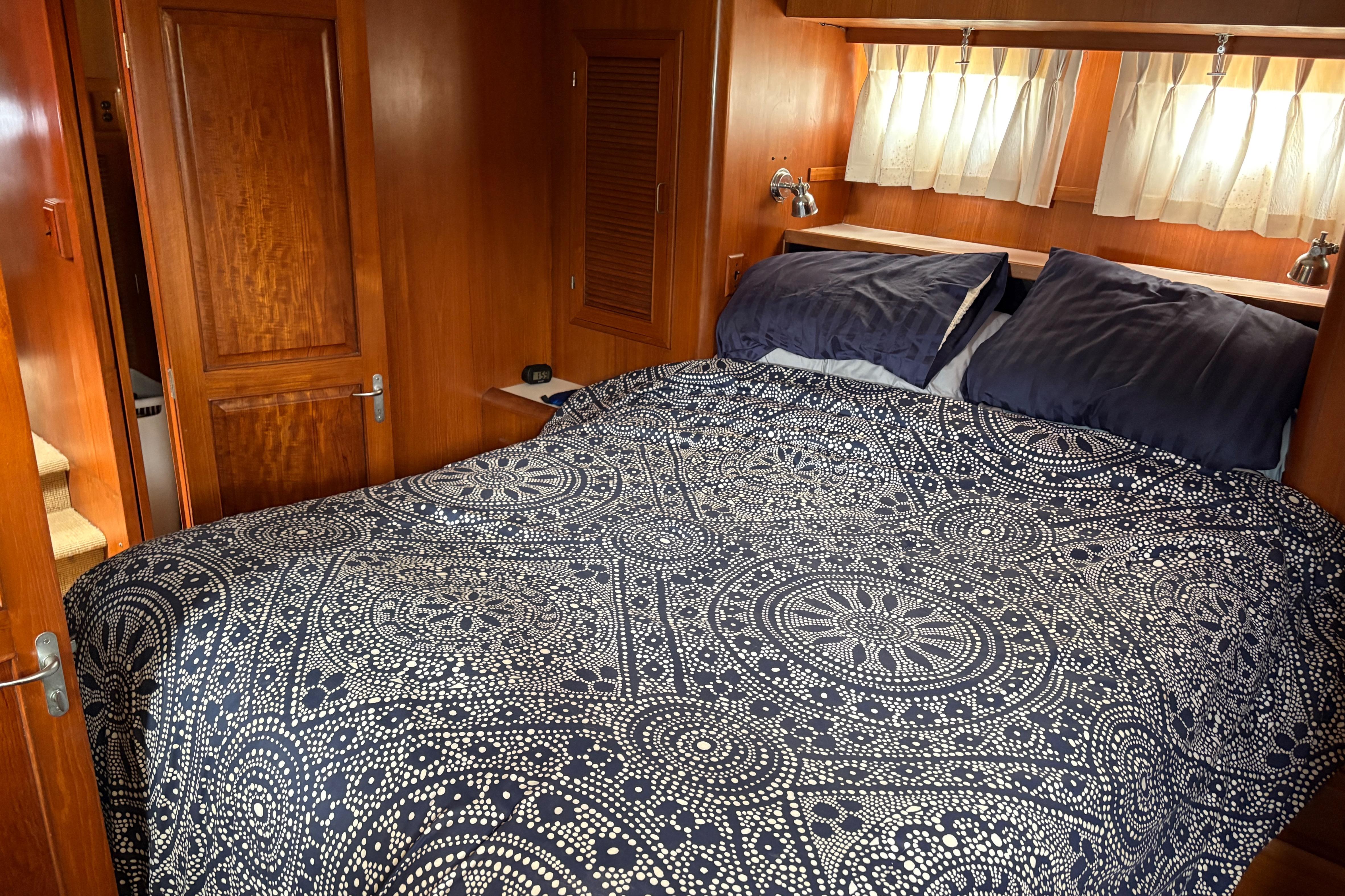 Cozy bedroom in 1990 Angel Pilothouse yacht with patterned bedding and wooden interior.