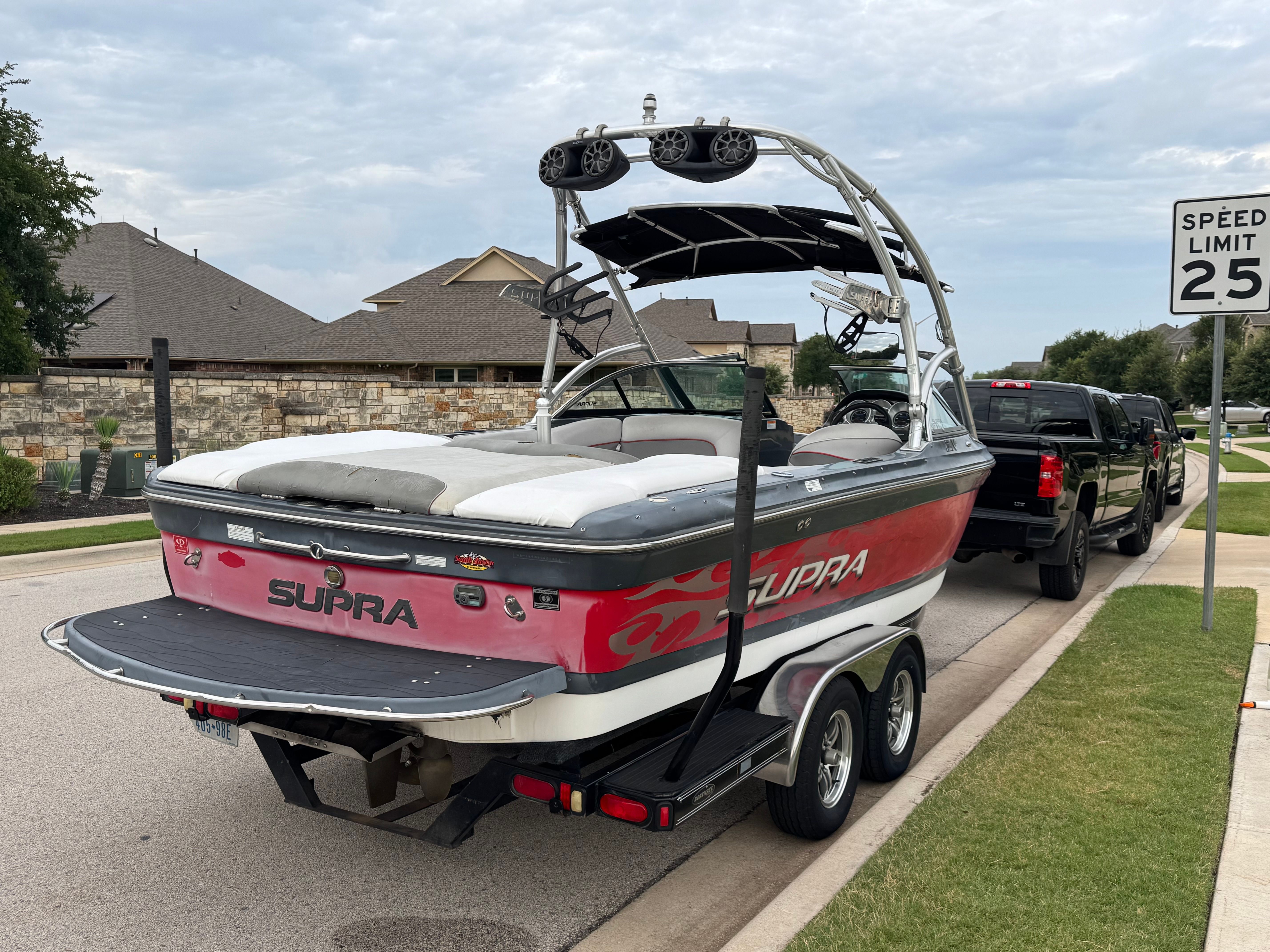 2008 Supra Launch 21 V on a trailer, parked on a residential street.