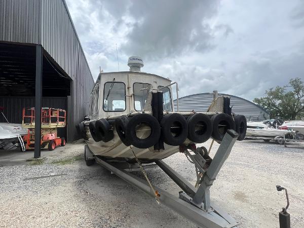 Custom Flat 28 Cabin Boat 2010 on trailer, surrounded by tires, parked near industrial buildings.