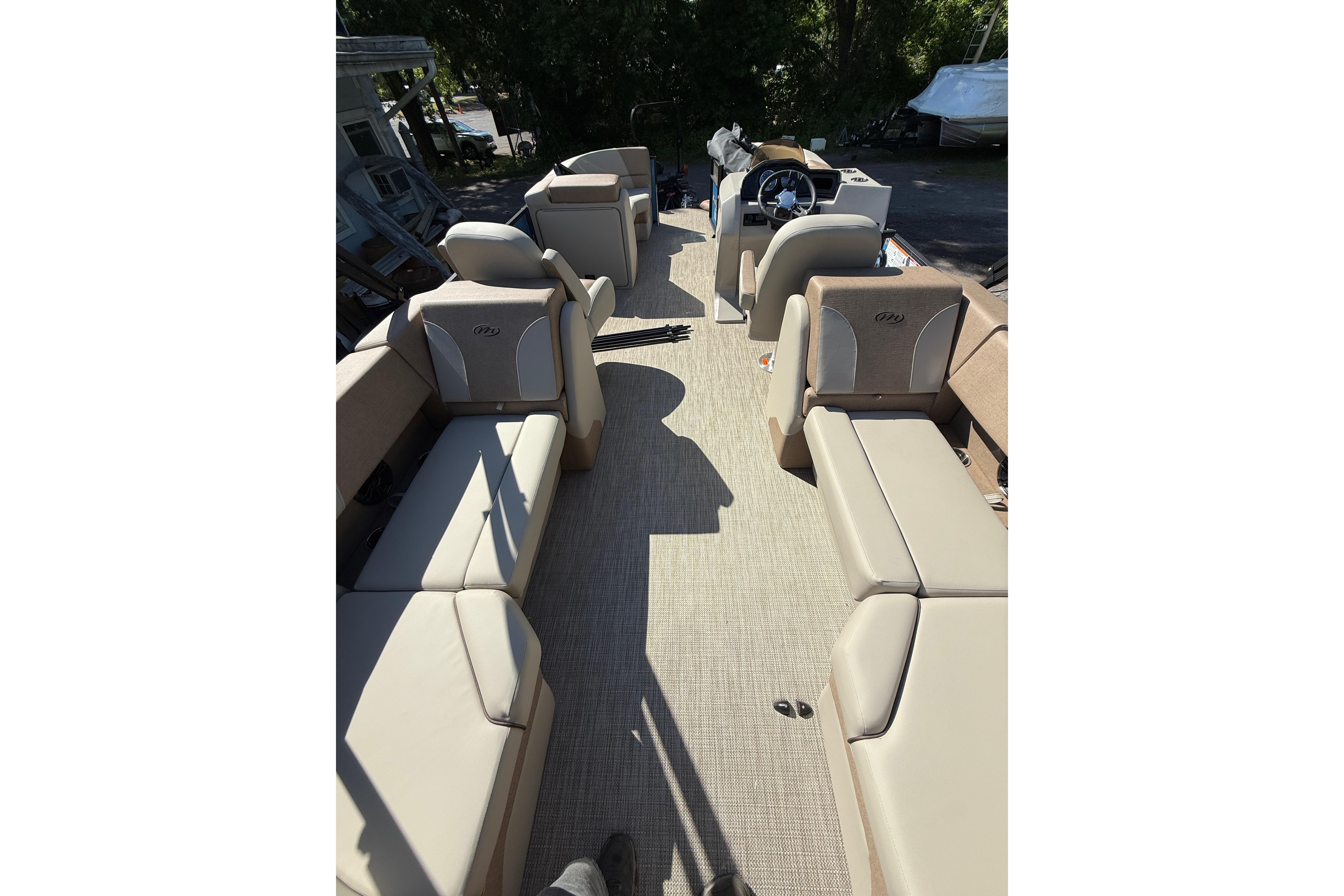 2027 Manitou Aurora RF 23 pontoon boat interior with beige seating and steering console.
