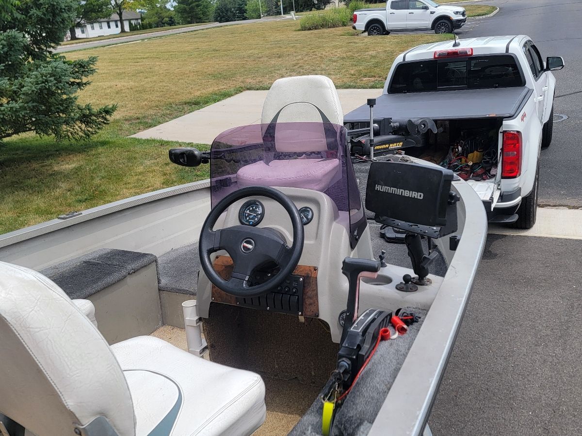 A 1997 Tracker Super Guide V16 boat with steering console and Humminbird fish finder, parked next to a pickup.
