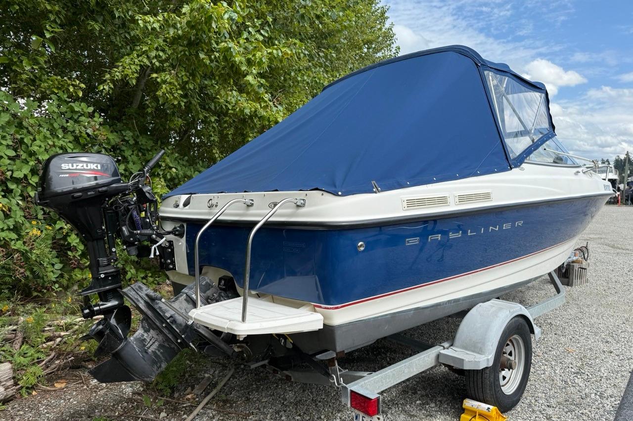 2005 Bayliner 210 Discovery boat with Suzuki outboard motor on trailer, blue cover.