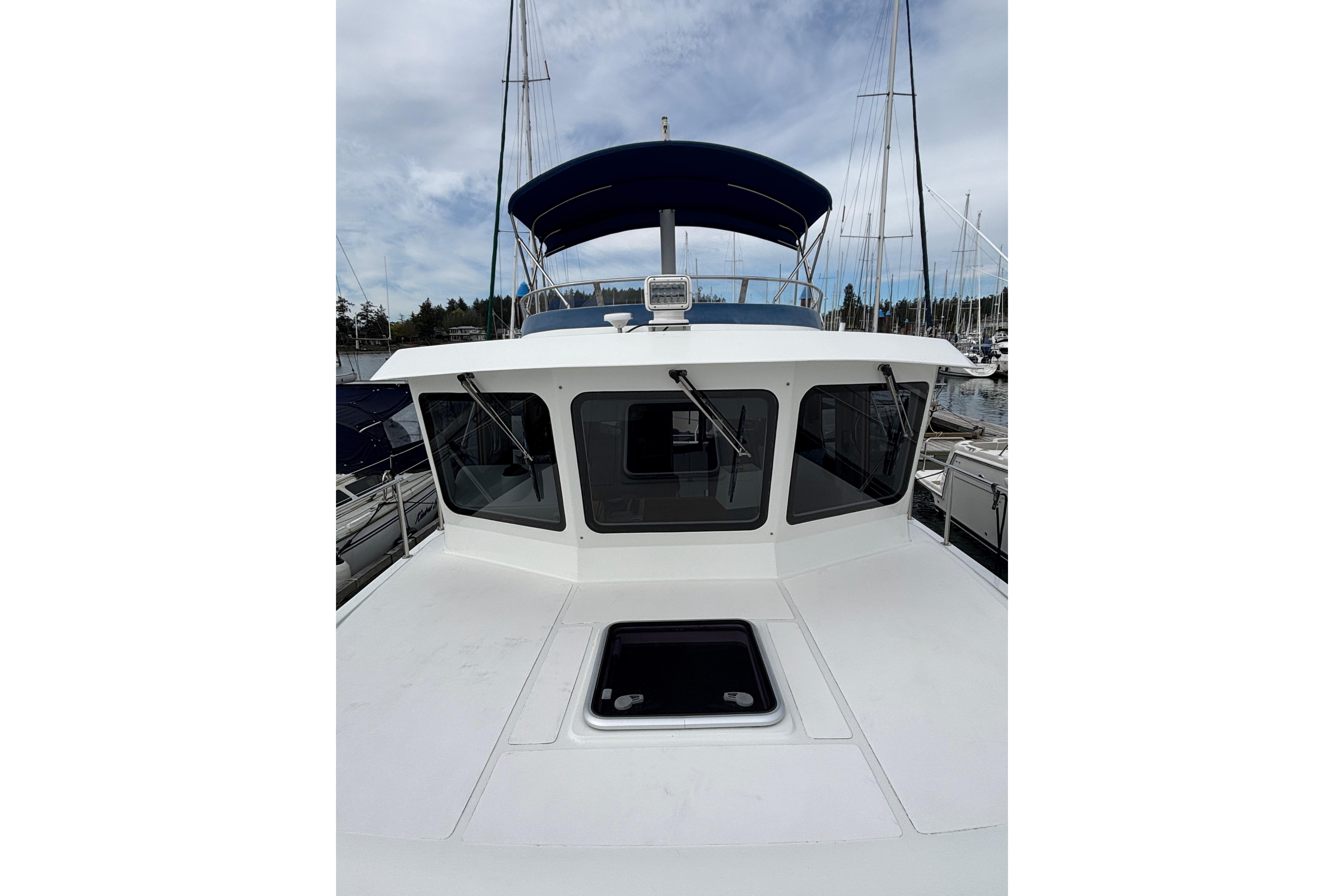 2006 Pilothouse Rockport Fast Trawler with blue canopy, docked at marina.