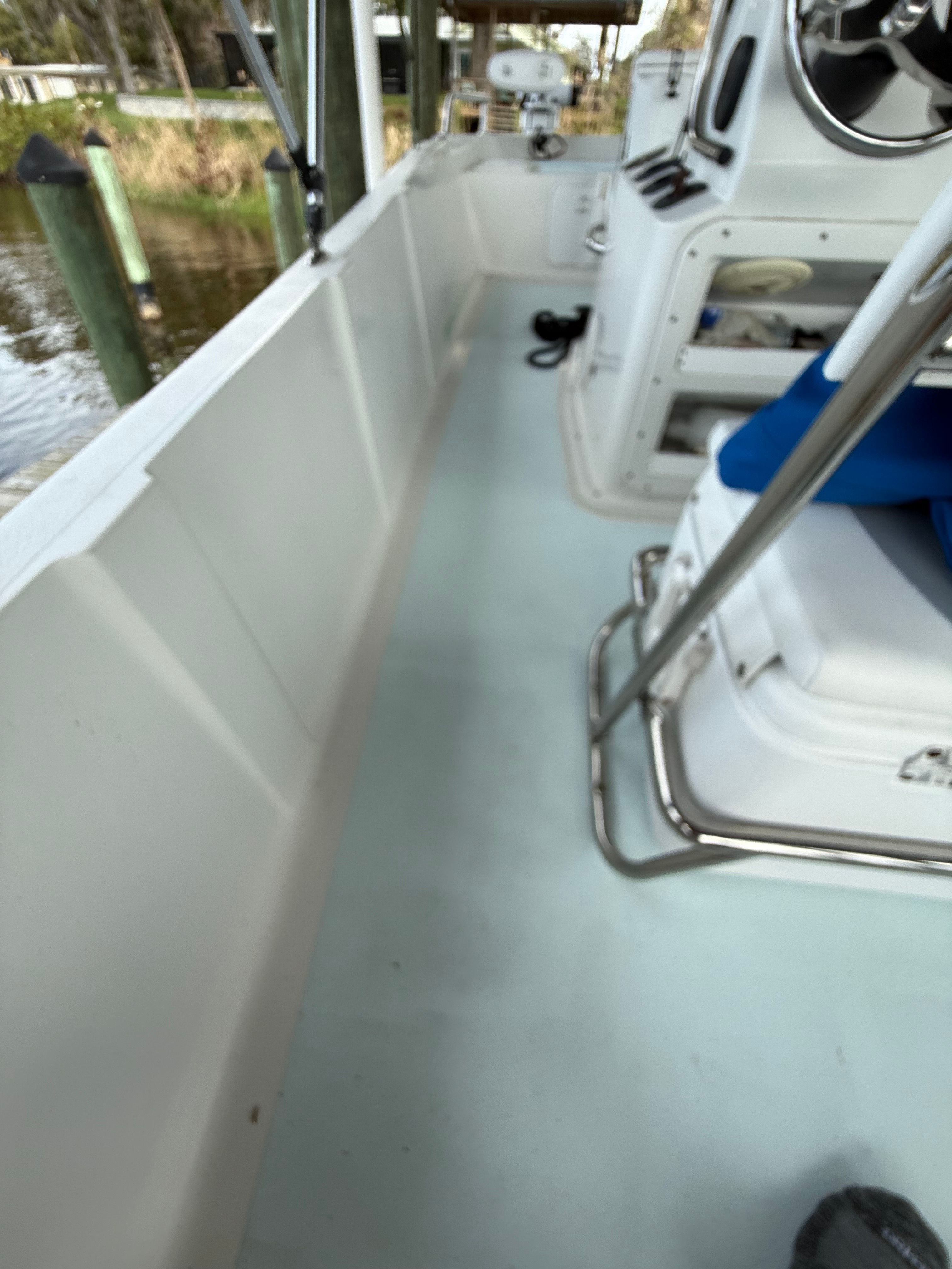 A boat with a white deck and blue seats, docked at a pier.