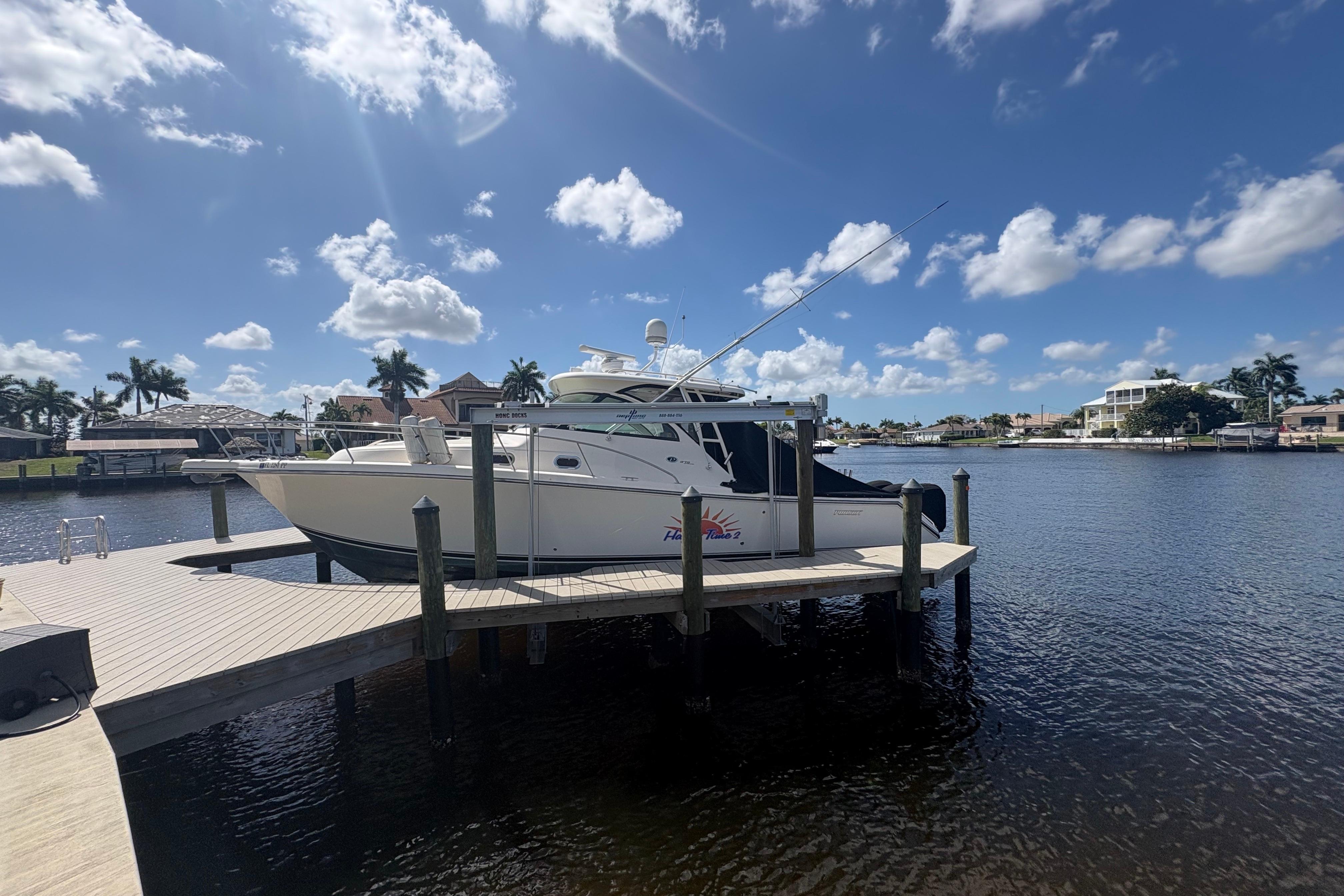 2011 Pursuit OS 375 Offshore boat docked on a sunny waterfront with palm trees.